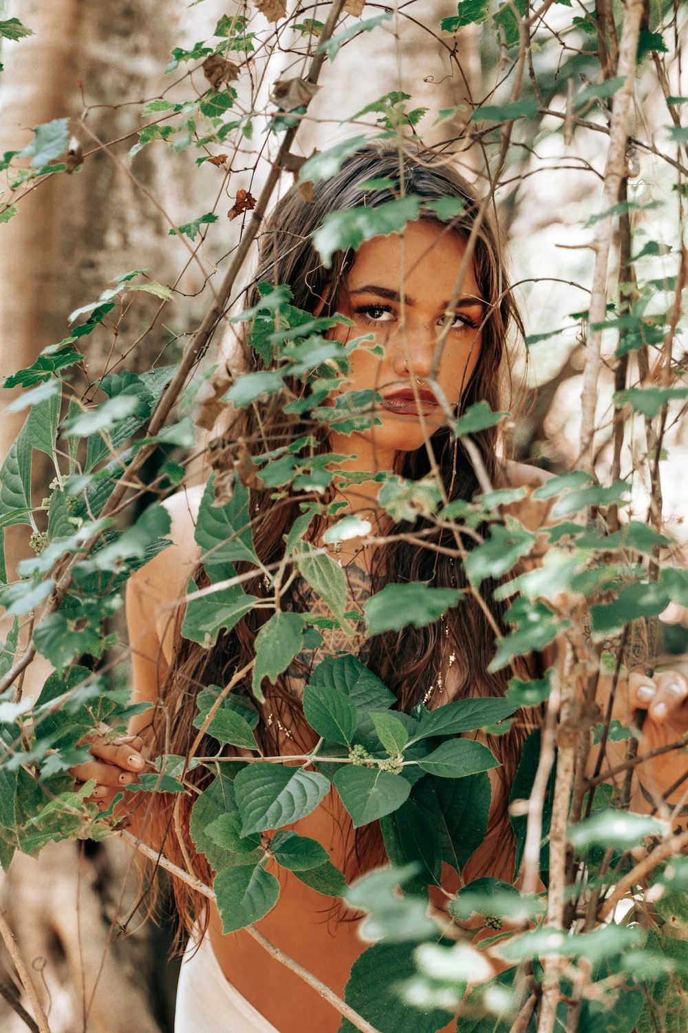 Artistic portrait framed by tropical leaves and natural greenery.