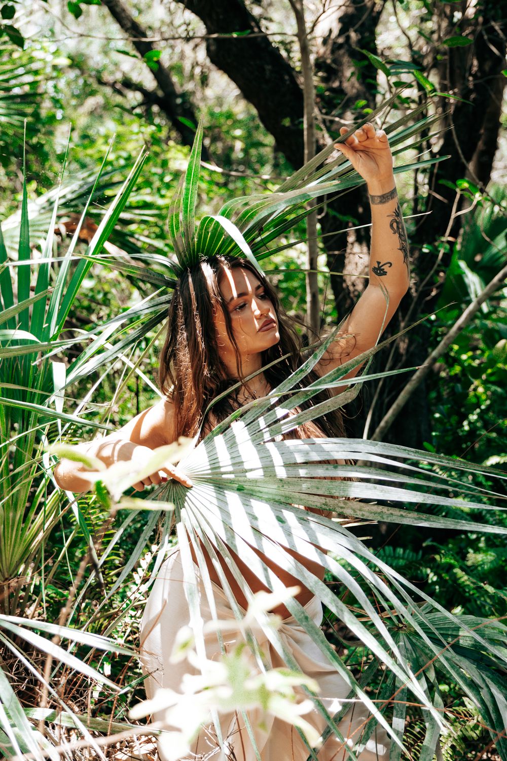 A dreamy photoshoot in a tropical setting with palm fronds and natural sunlight filtering through the foliage.