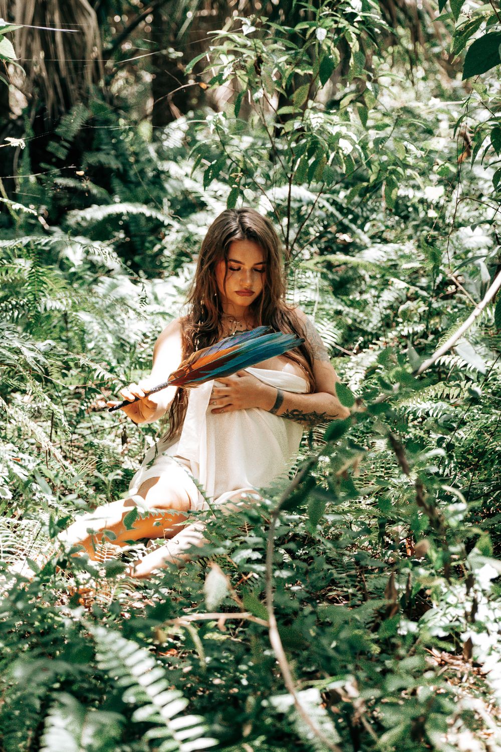 An artistic portrait session among lush greenery and white flowers in a garden setting.