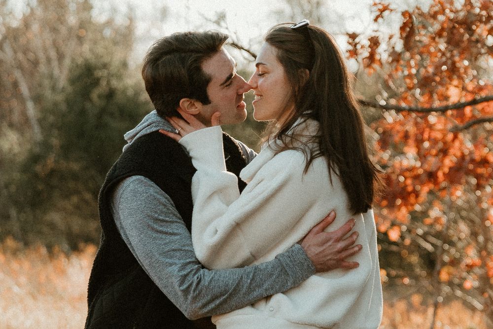 A romantic embrace captured in warm autumn light with orange leaves in the background.
