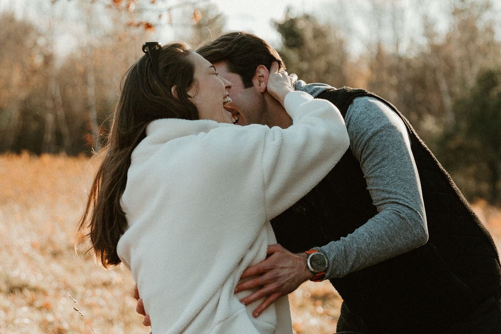 Romantic couple sharing intimate moments in an autumn forest setting with fallen leaves and branches.
