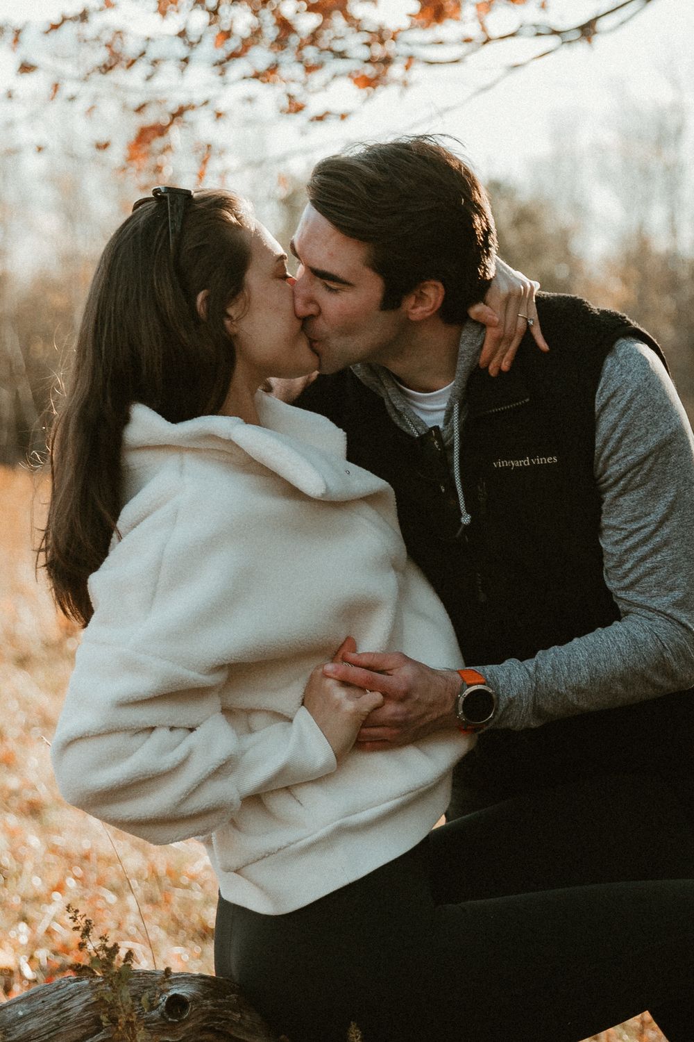 Intimate couple's photoshoot with cozy sweaters against fall foliage background.