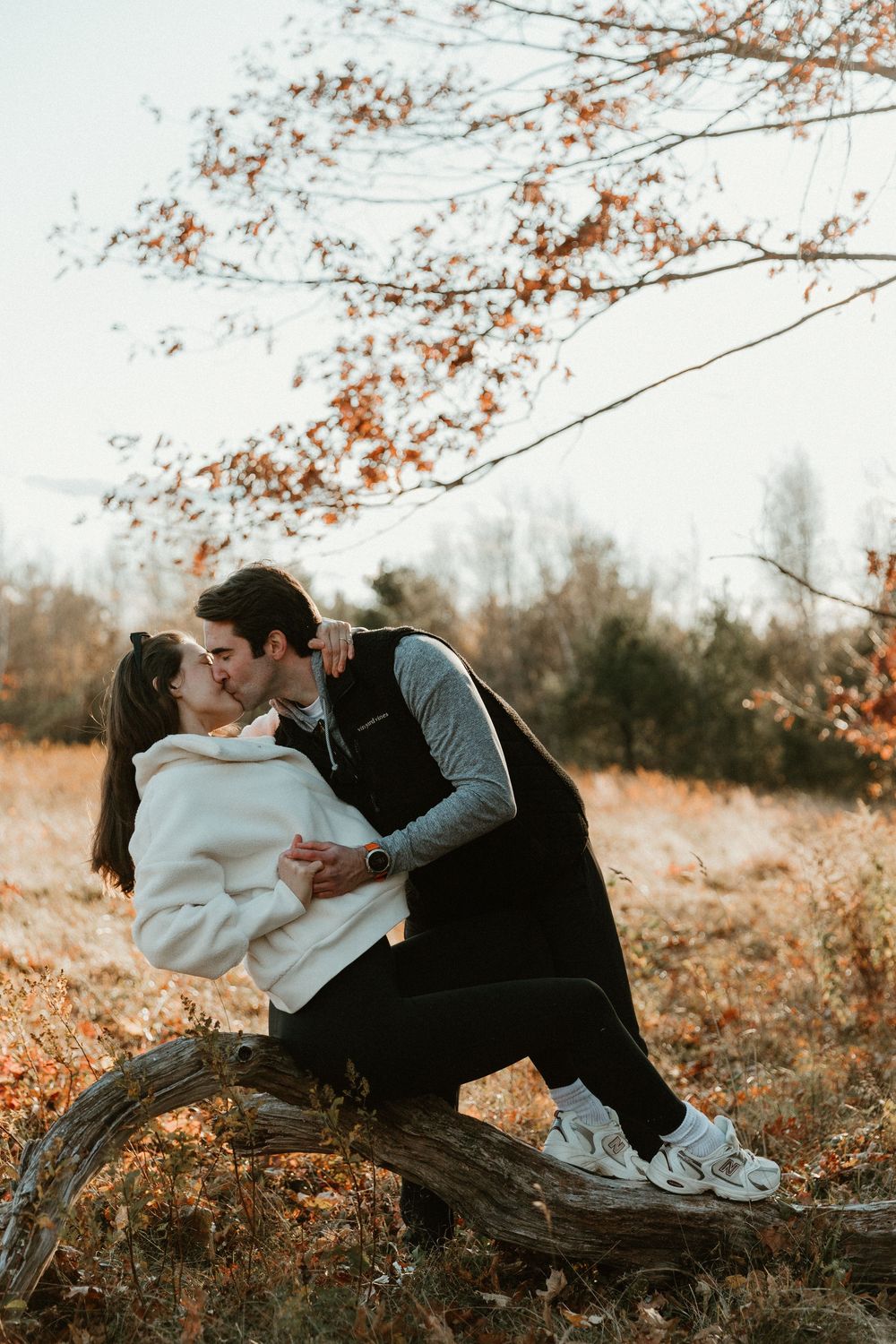Romantic autumn photoshoot on fallen tree trunk with soft natural lighting.