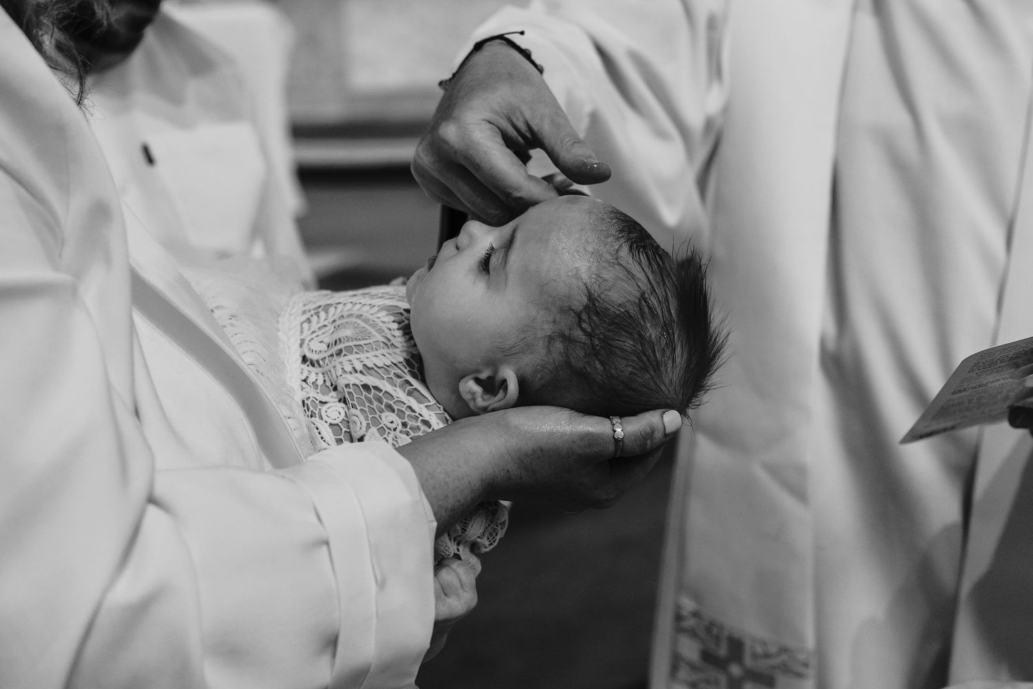 Medical professionals carefully examine a newborn baby in a black and white vintage photograph.