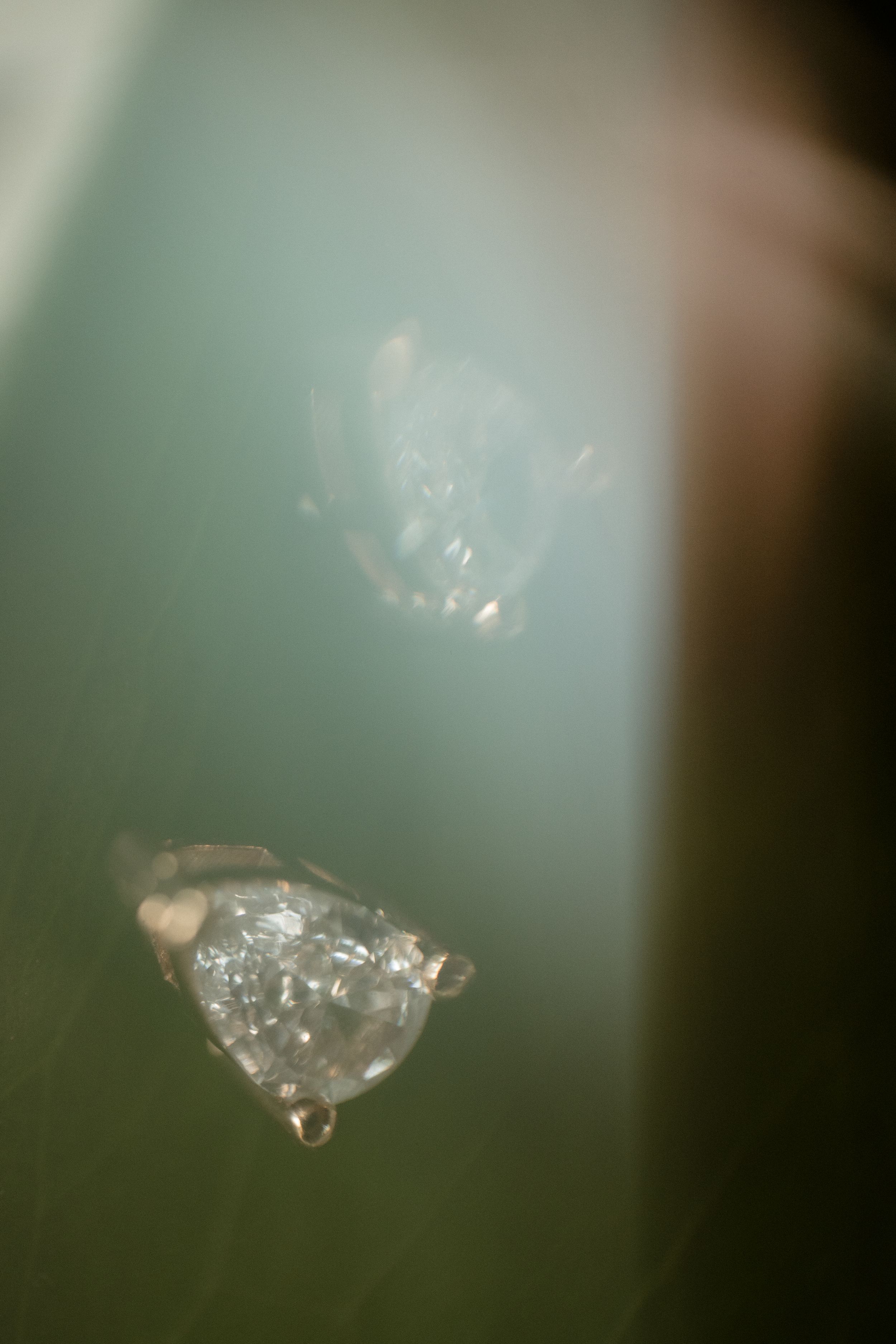 Macro shot of a sparkling diamond or crystal against a soft green background.