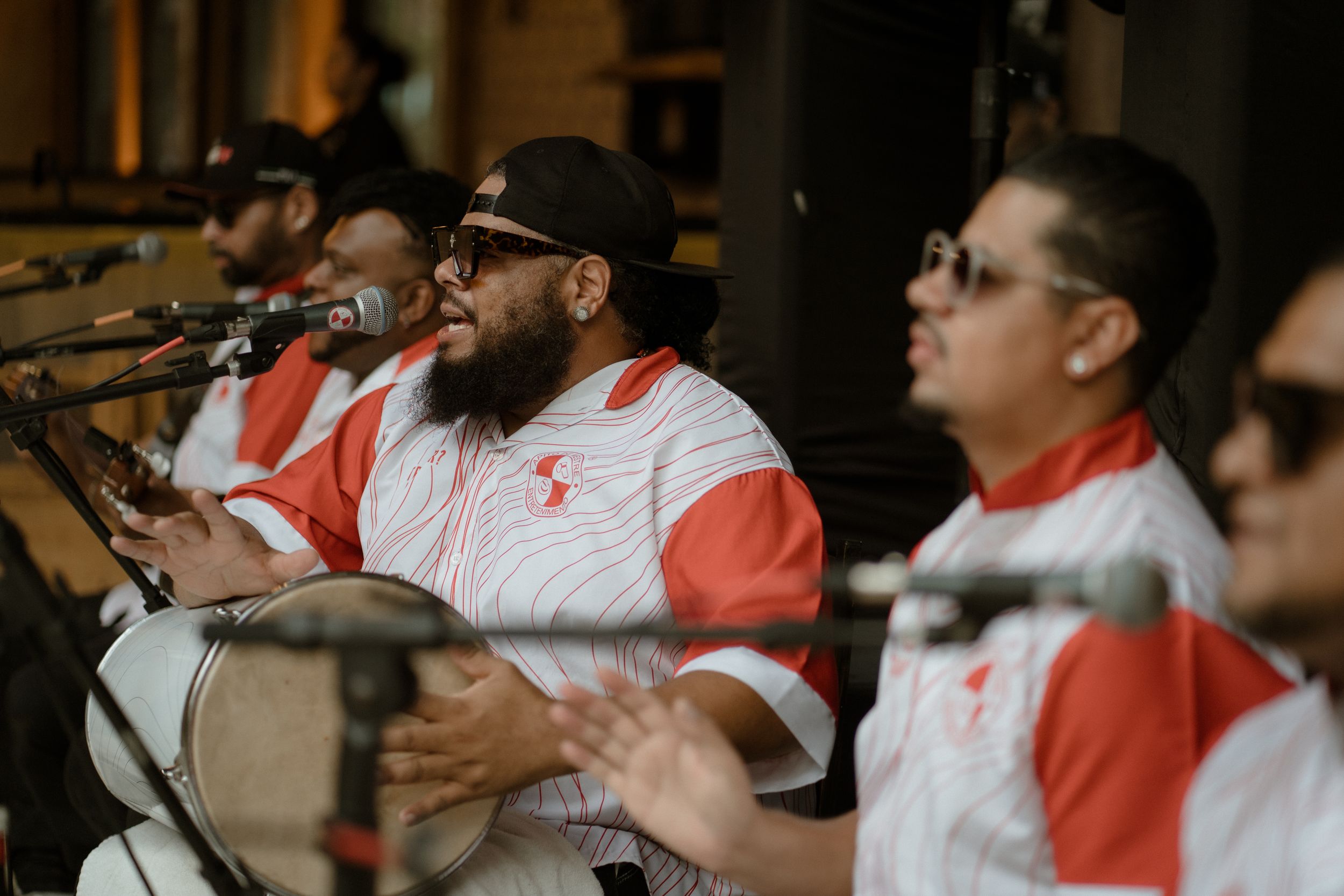 Musicians in matching red and white uniforms perform at an outdoor event.