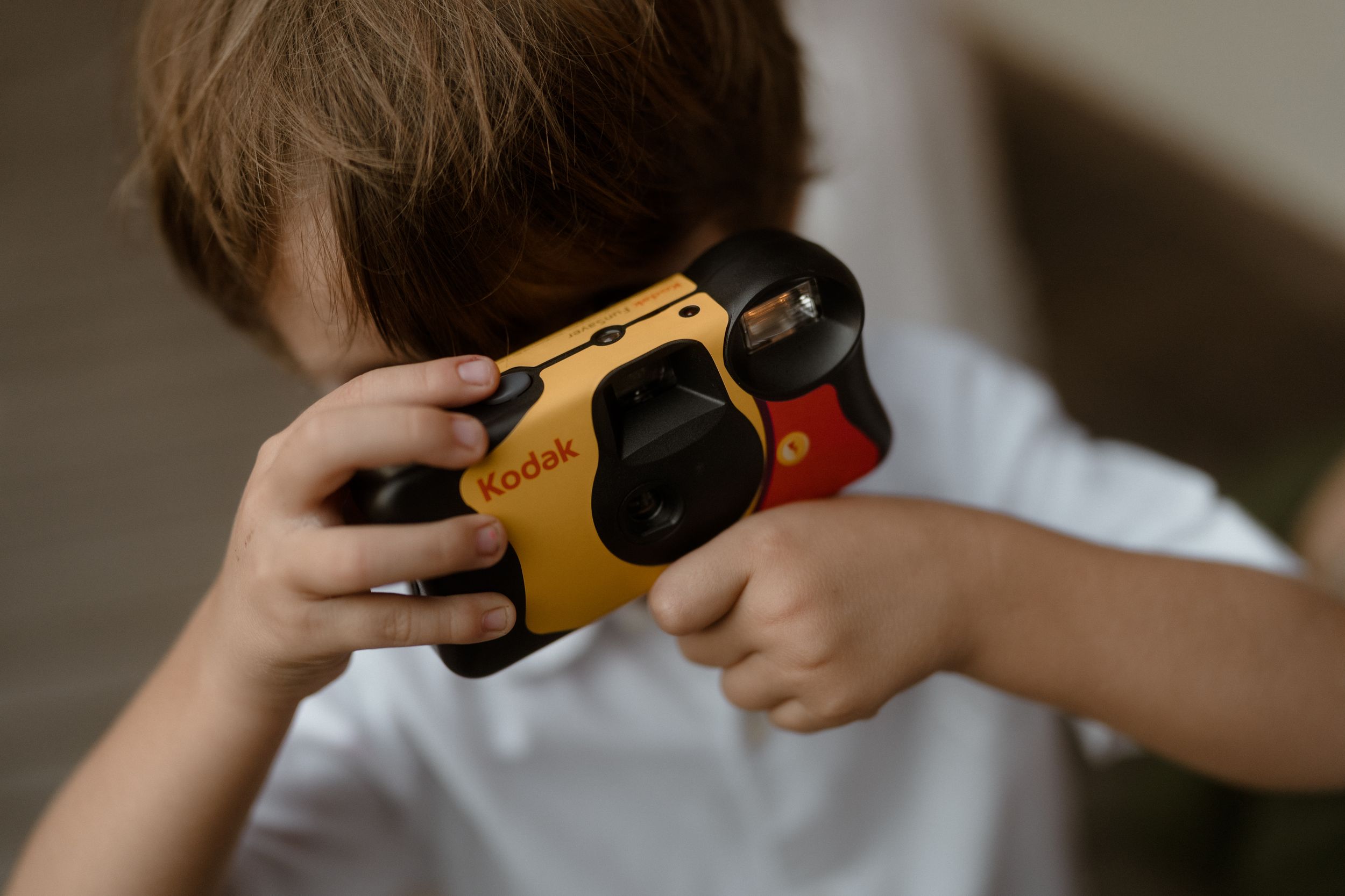 Close-up of small hands holding a yellow toy camera.