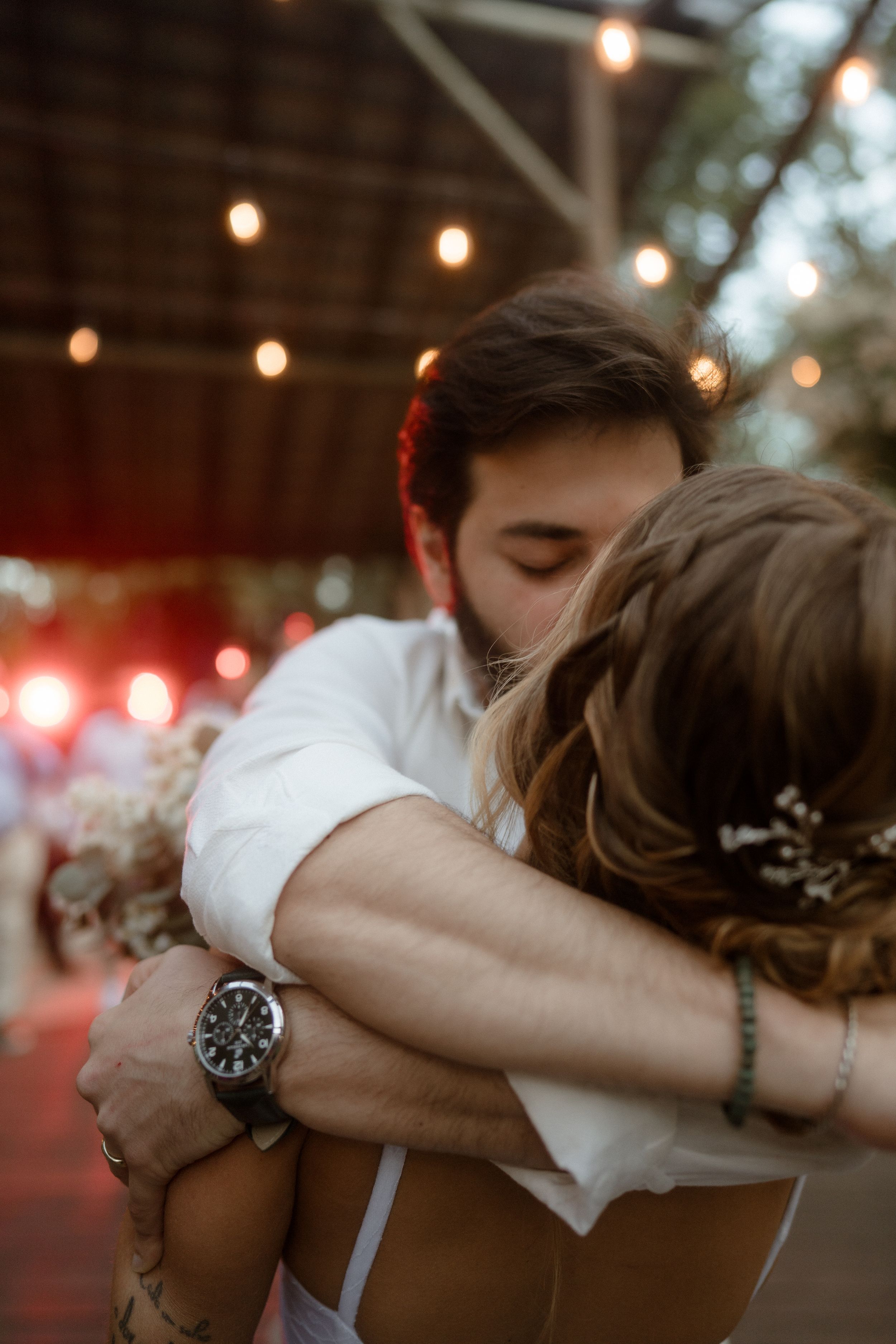 A romantic slow dance moment captured under warm string lights at dusk.
