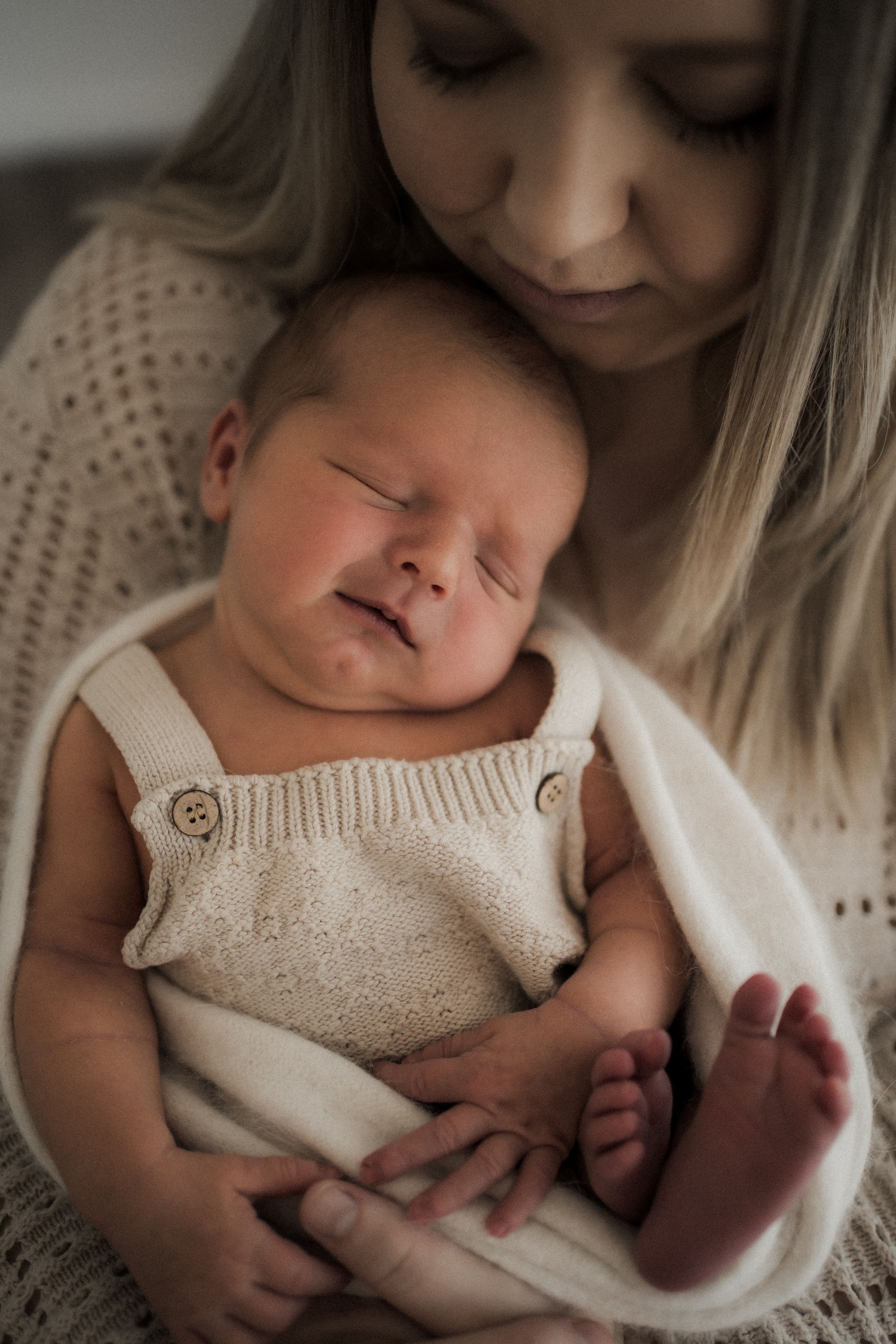 A tender moment captured in a series of photos showing a newborn baby being cradled in soft cream-colored knit clothing.