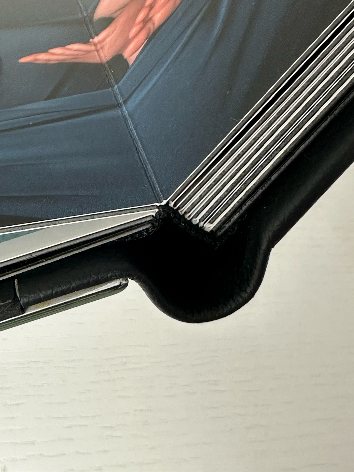Close-up of a folding smartphone hinge corner showing layered display and black protective case detail. Photo book