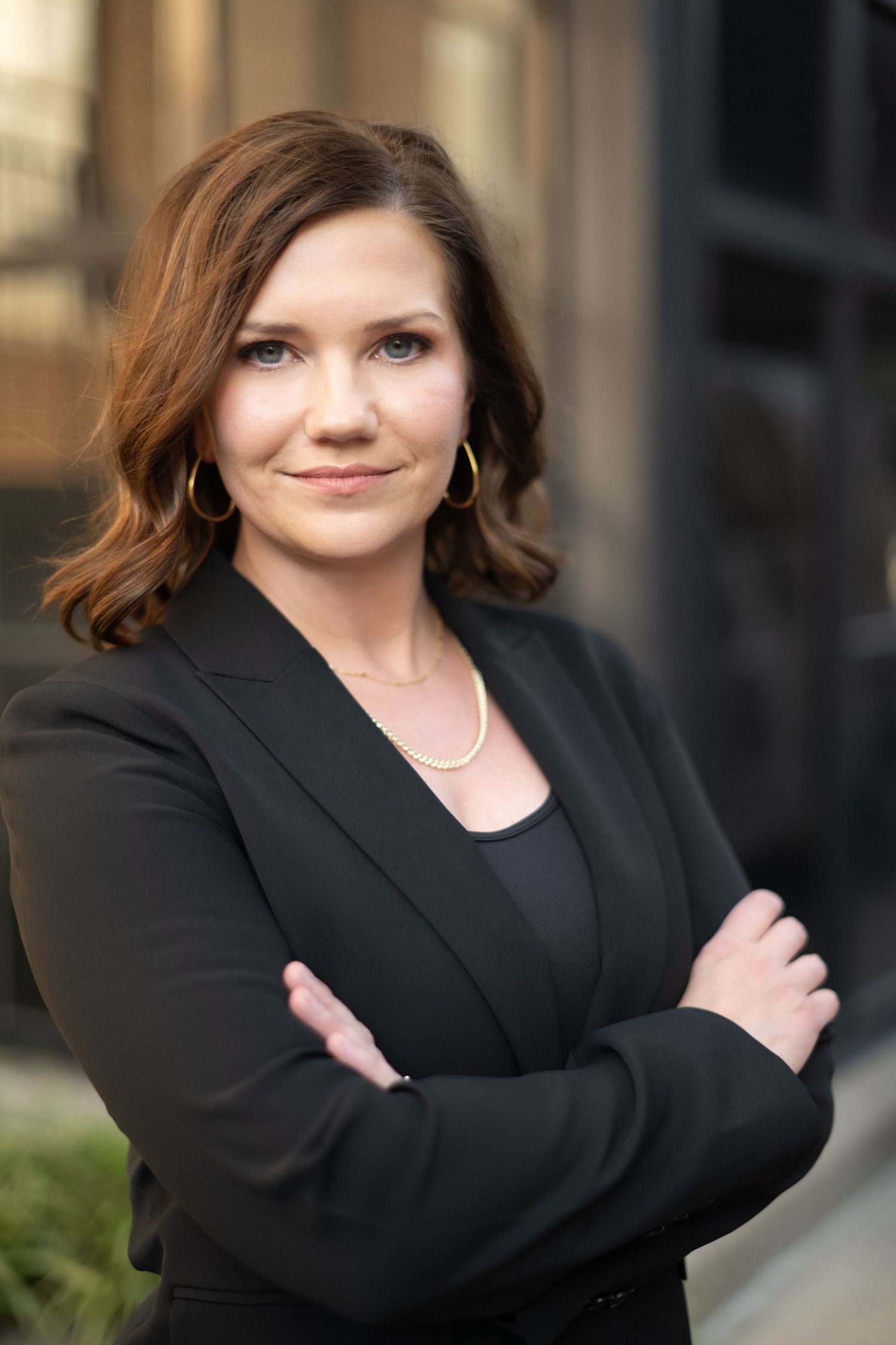 Professional headshot of attorney in black blazer against urban backdrop in downtown Franklin.