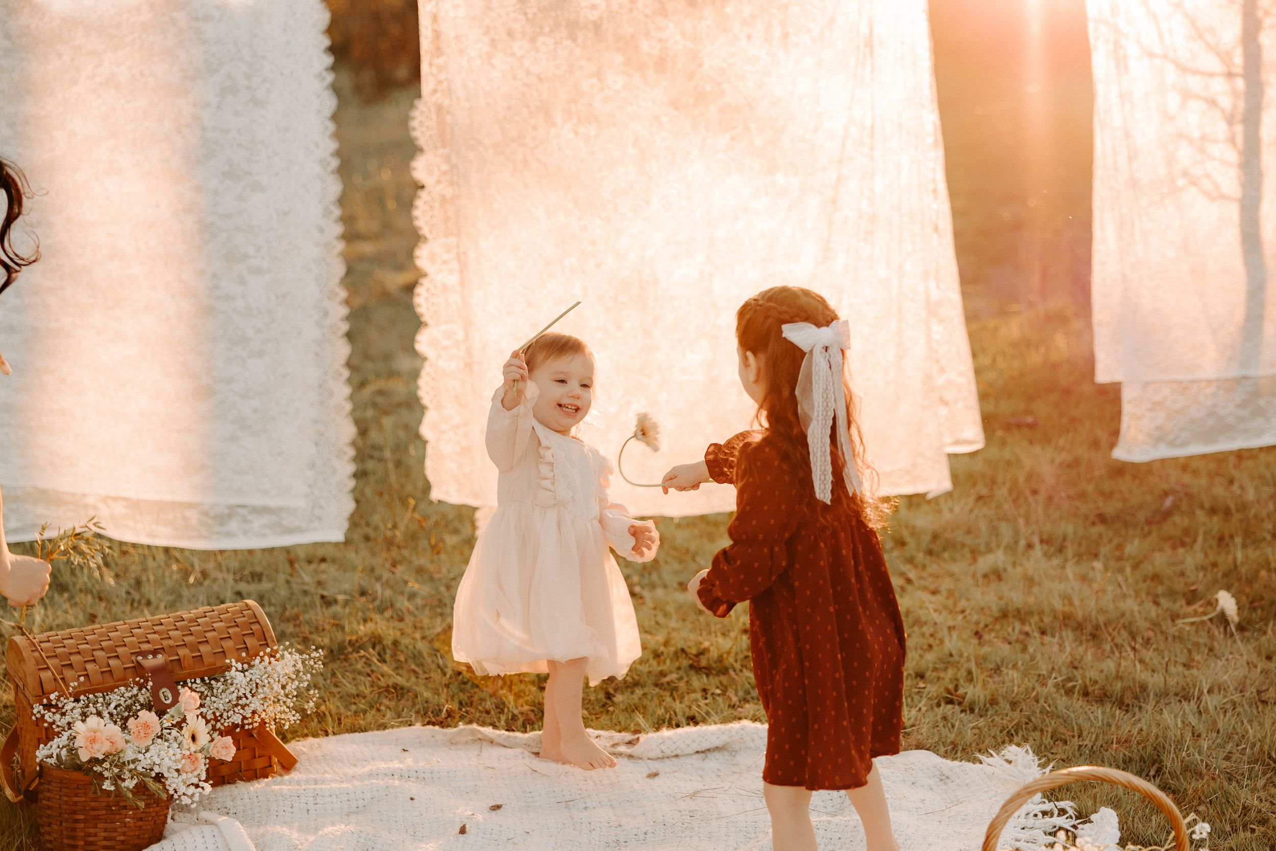 Vintage-inspired maternity scene with white linens hanging on clothesline at sunset.
