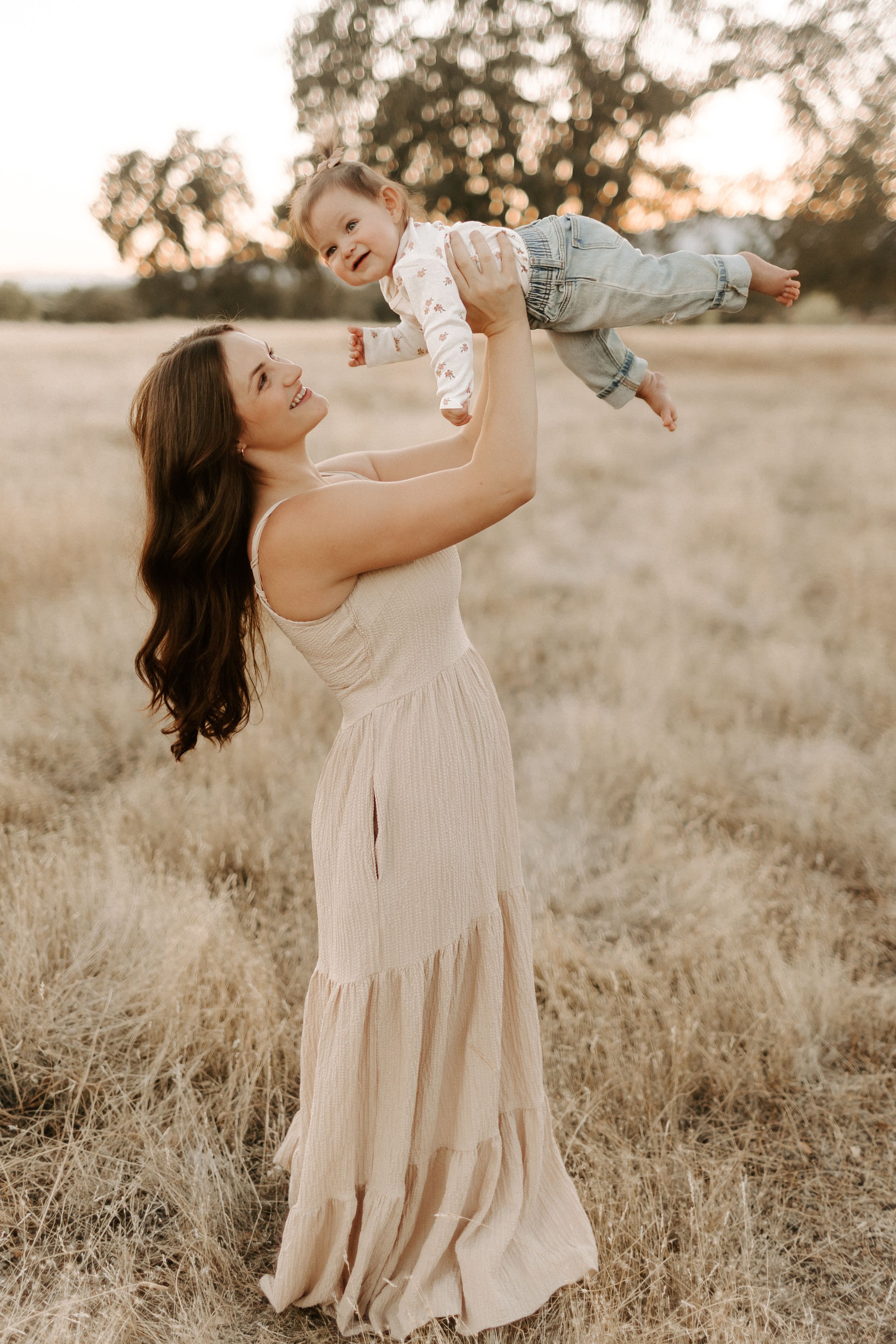 Joyful moments captured in flowing cream dress during golden hour in rustic field.