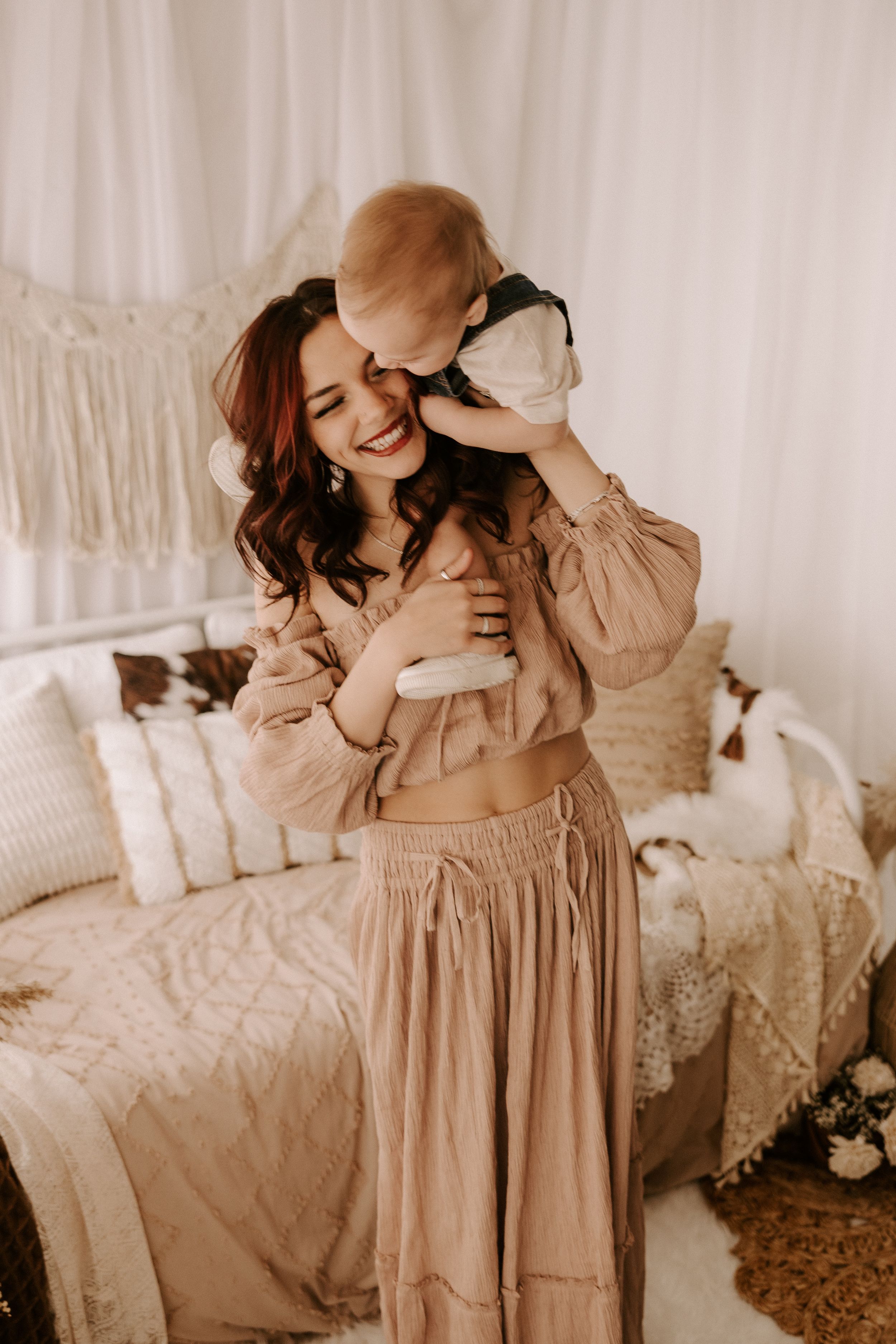 Indoor lifestyle maternity photos with soft beige dress against white backdrop.