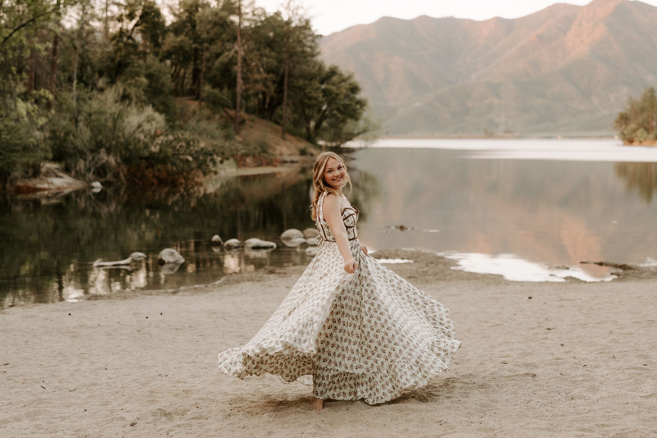 Sunset maternity photos by a mountain lake with dramatic landscape backdrop.