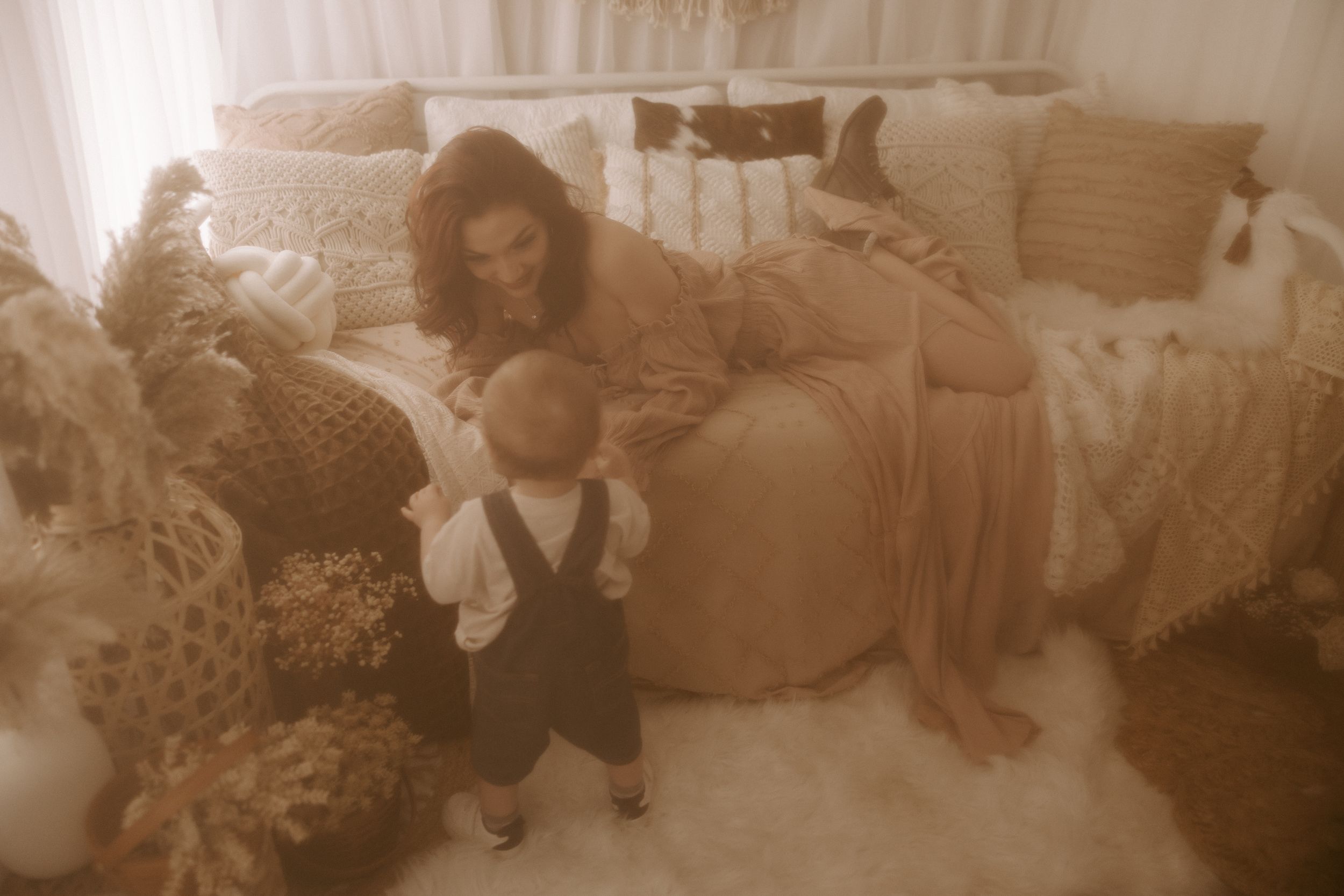Vintage-toned indoor maternity session with soft textures and natural lighting.