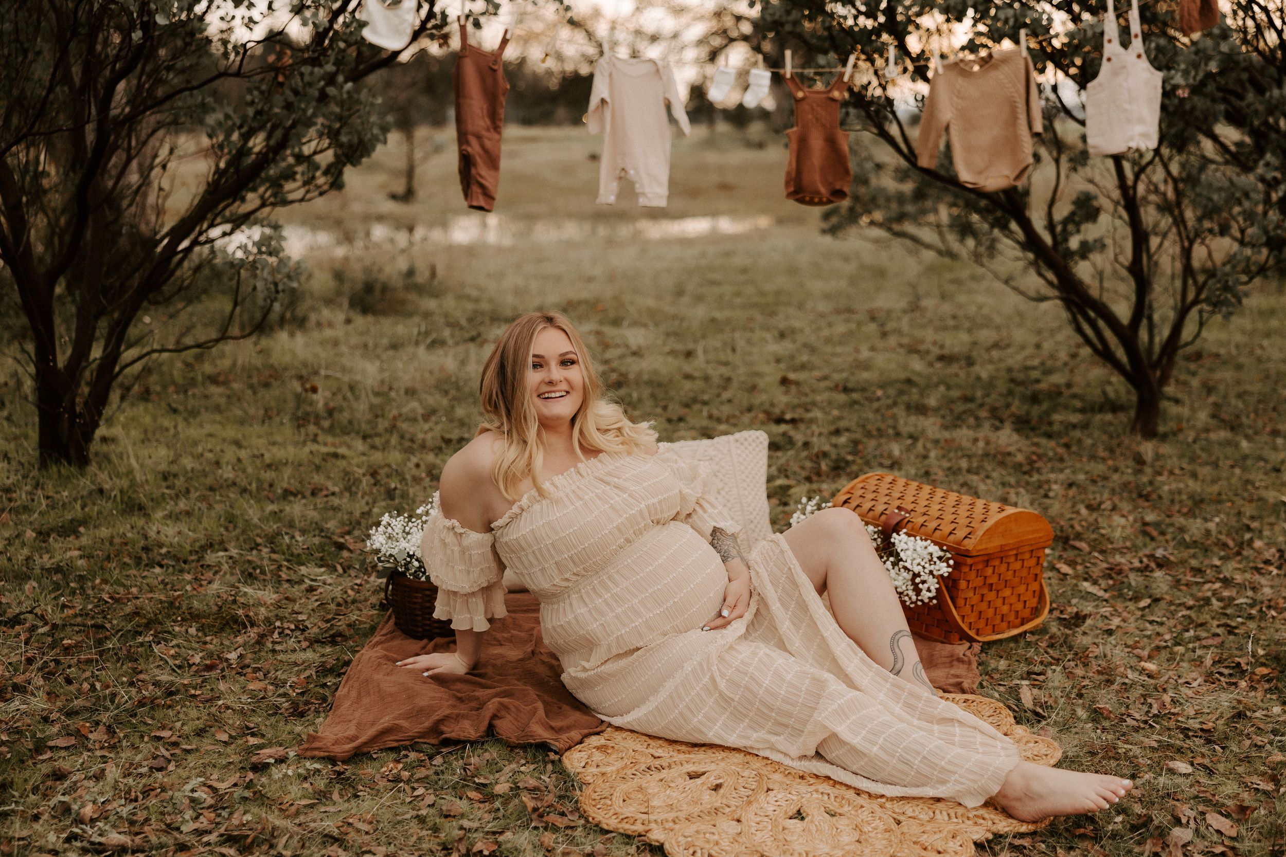 Outdoor maternity photography with vintage picnic setup and cream colored dress.