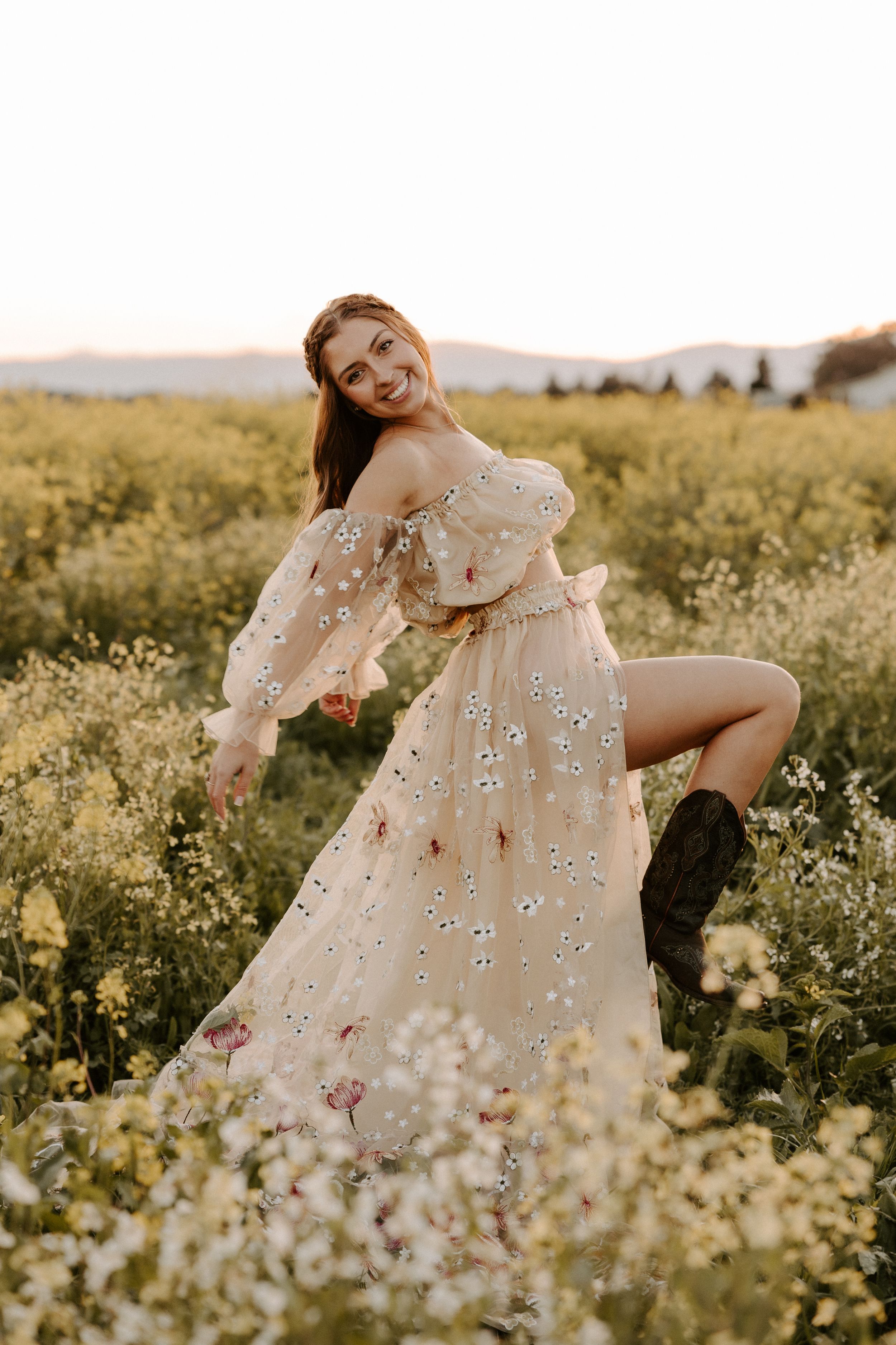 Floral white dress flowing in a golden wildflower field during sunset photoshoot.