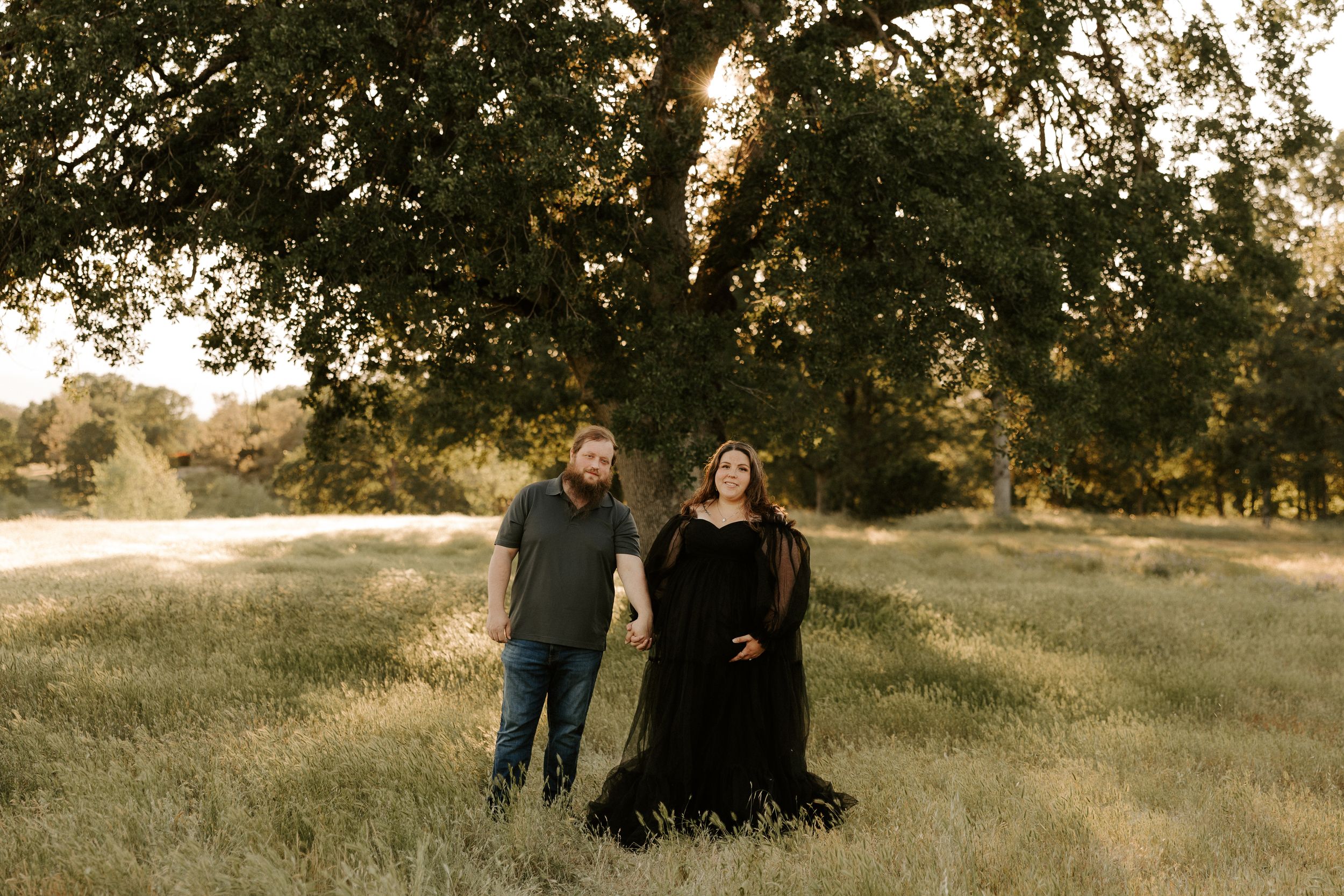 Outdoor maternity photoshoot with natural lighting and oak trees in background.