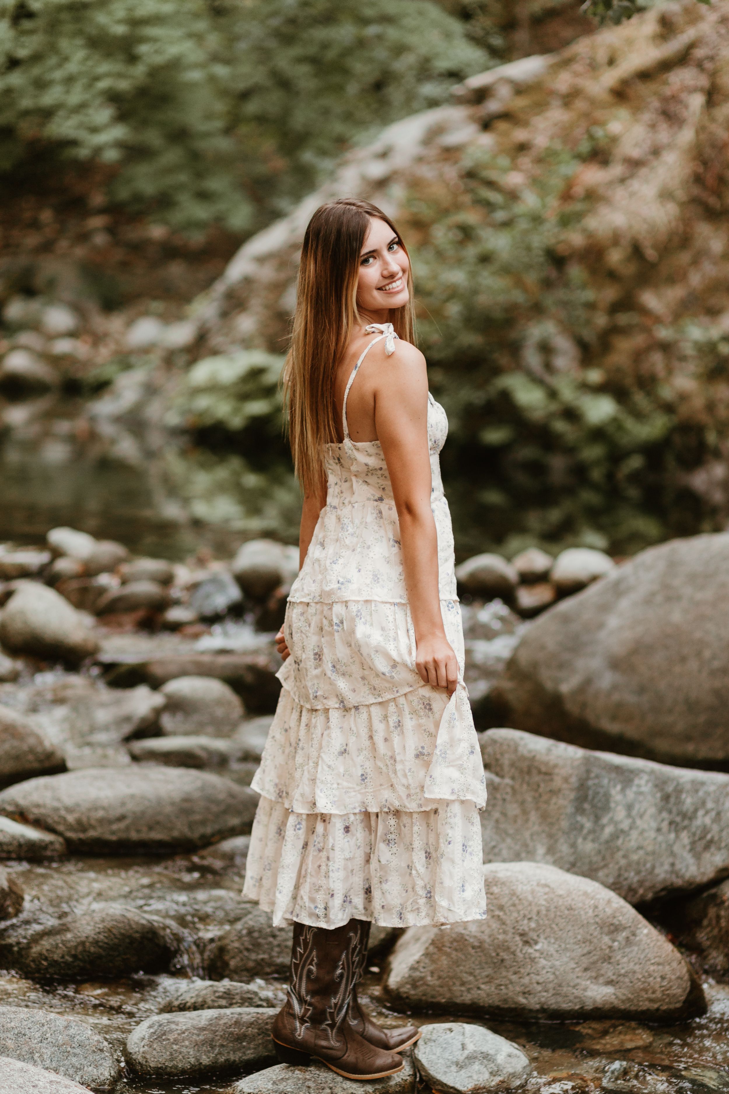 A cream lace dress paired with rustic boots creates a boho look among river rocks.