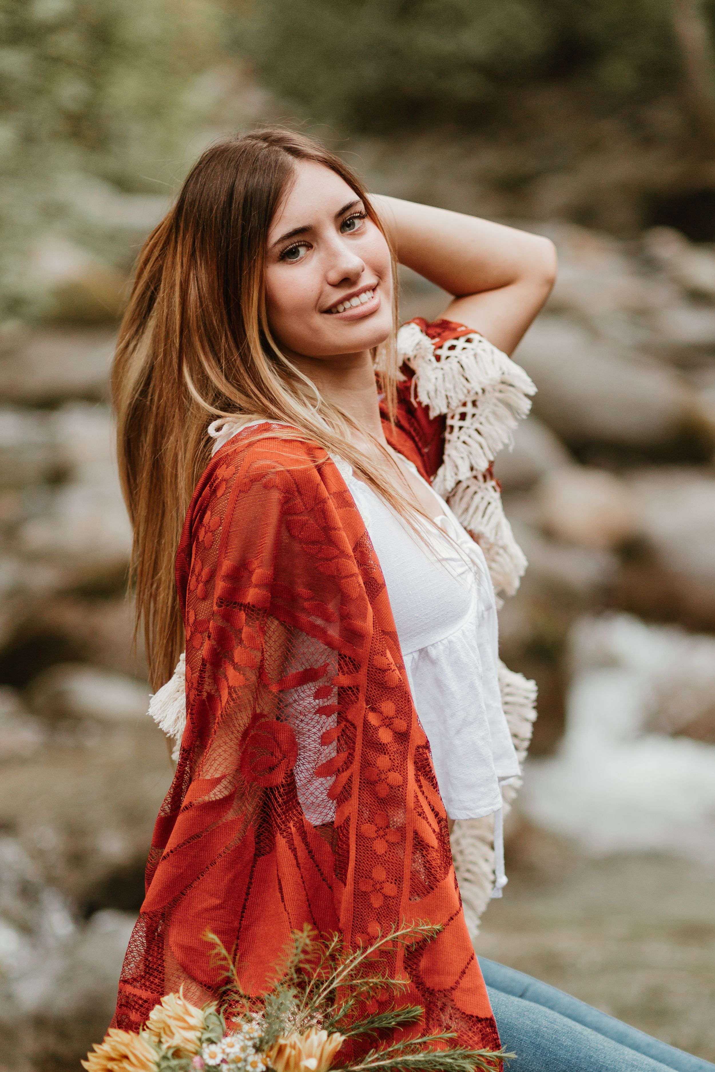 Bohemian styled portrait session featuring a red velvet kimono and white lace top by a stream.