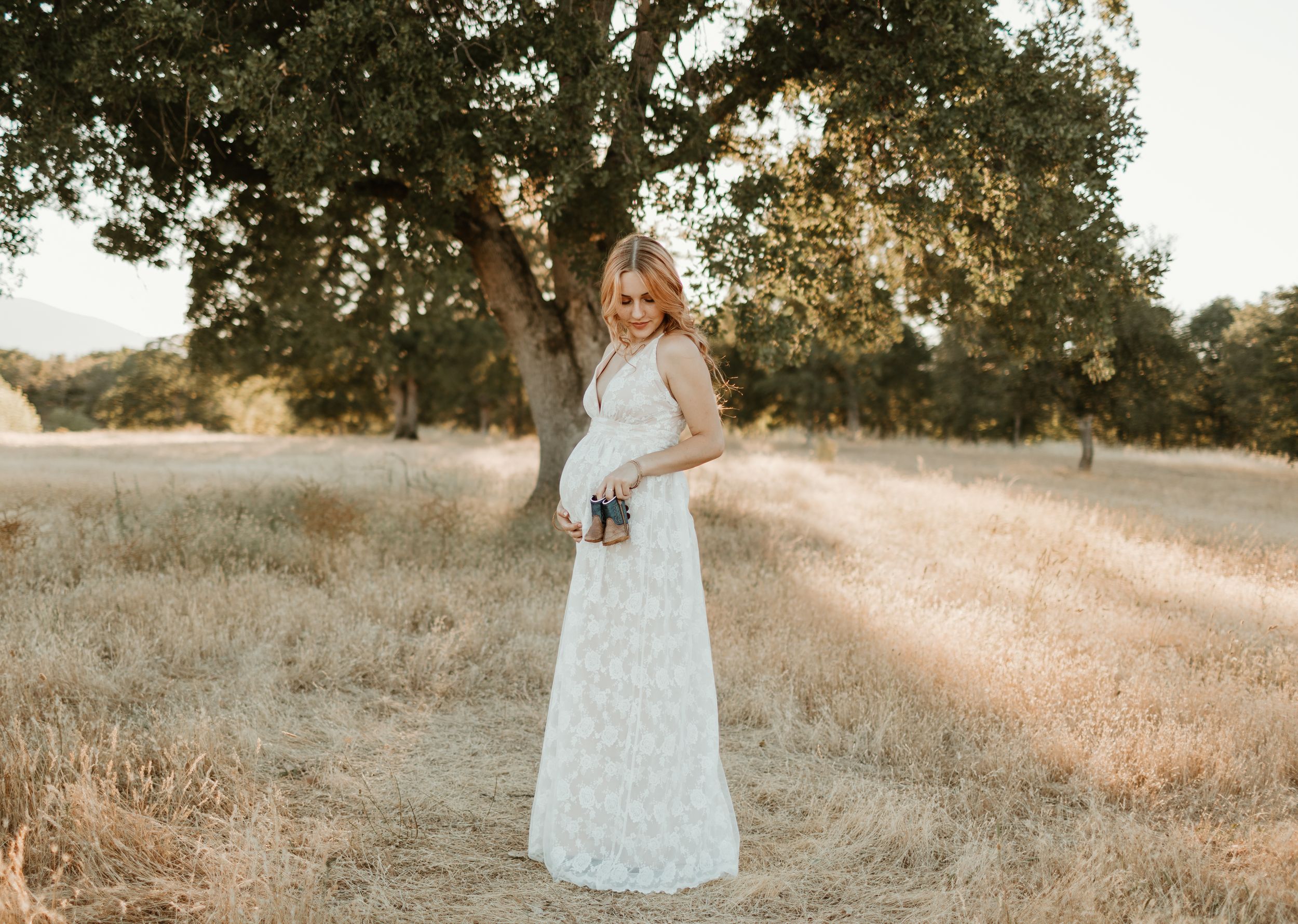 A delicate white dress catches light in a rustic field setting during golden hour.