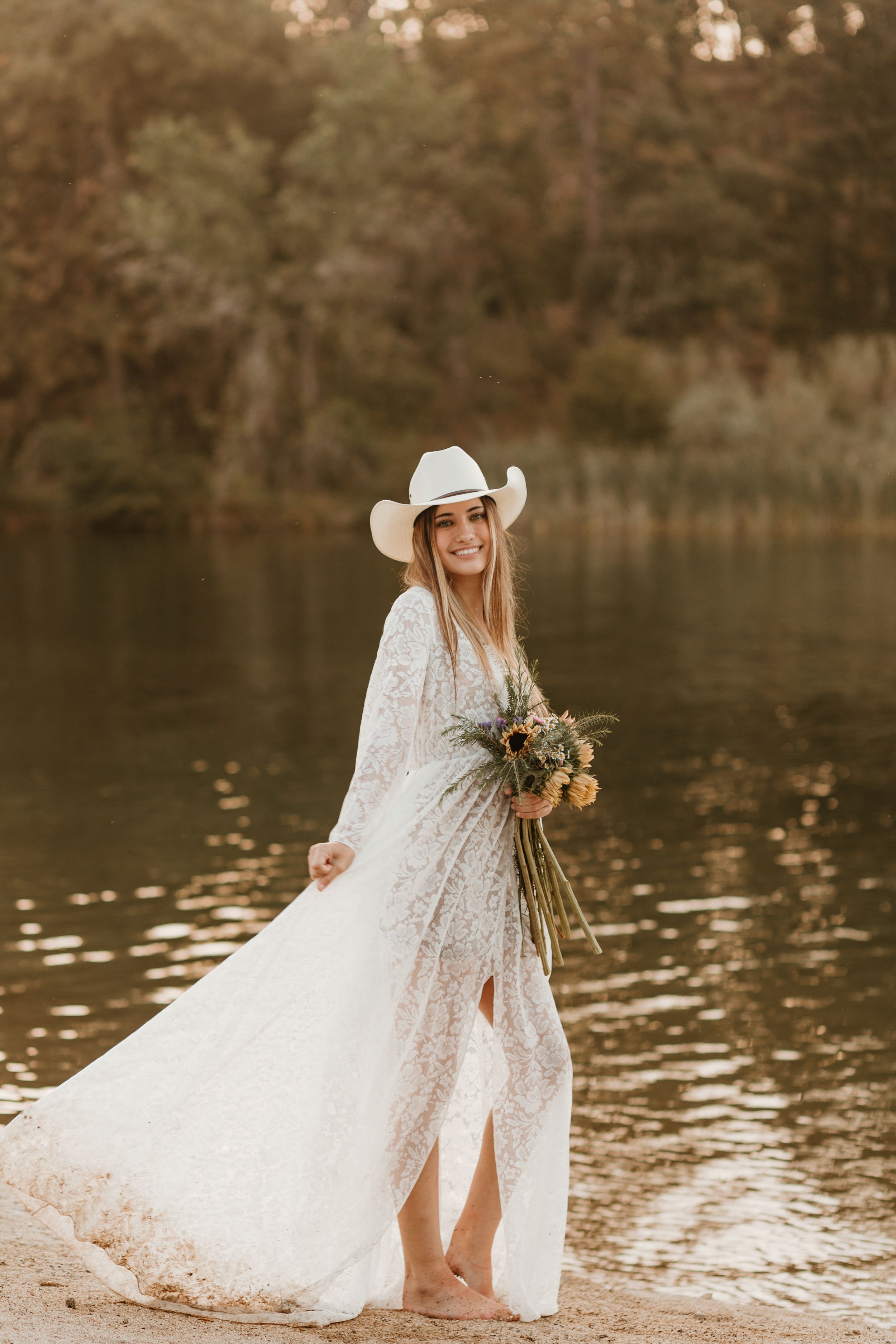 White lace dress and cowboy hat create romantic western style by the water.