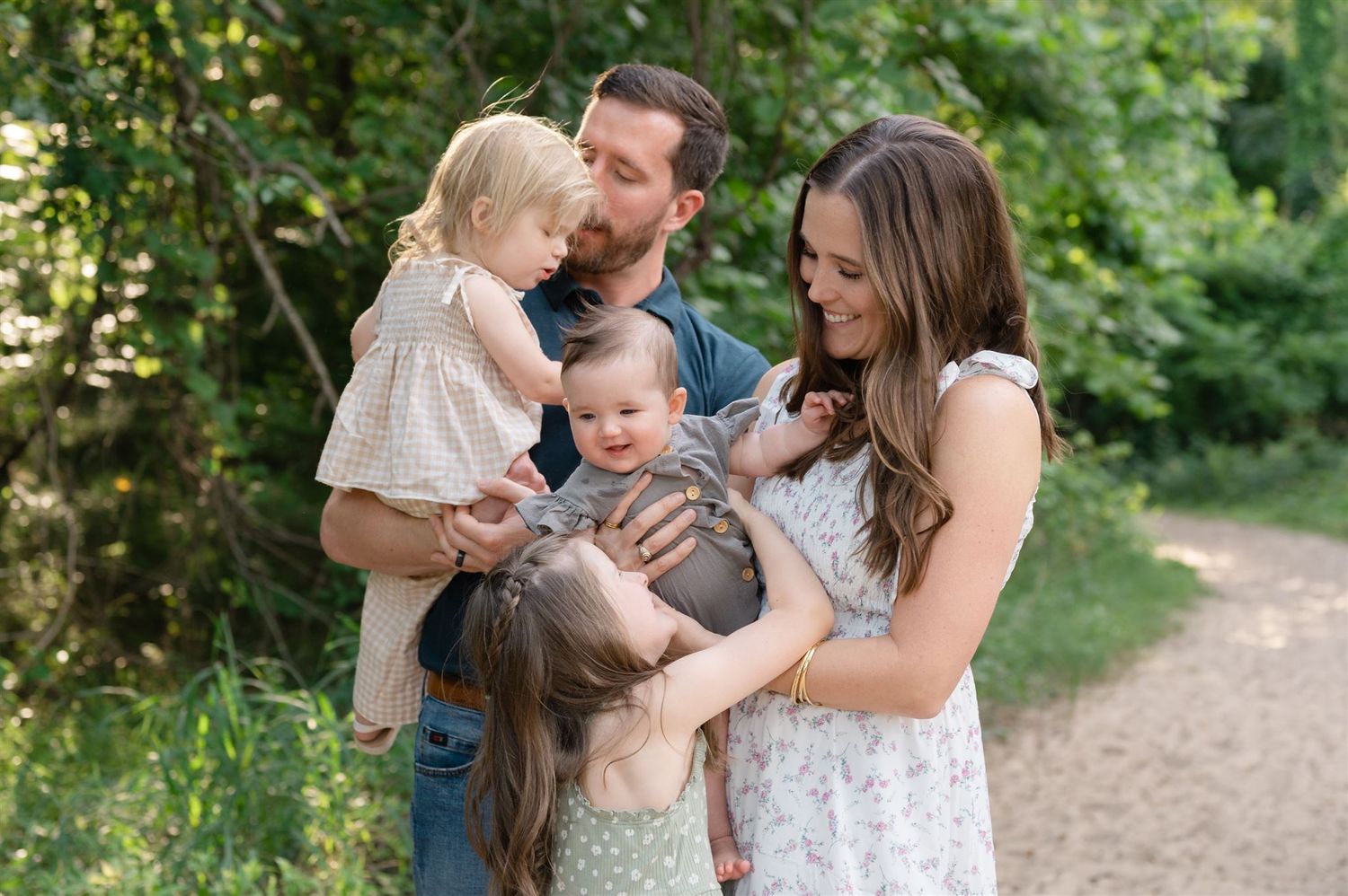 A loving family enjoying a tender moment together on a natural path surrounded by lush greenery.