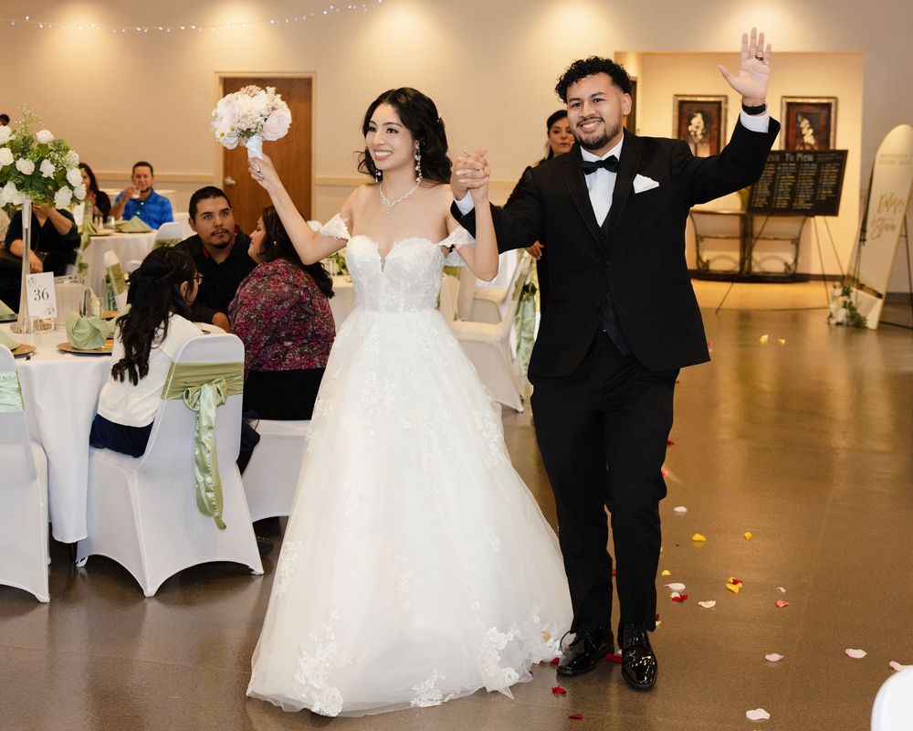 Joyful bride and groom make their entrance at the wedding reception, waving to guests; vibrant wedding photography.