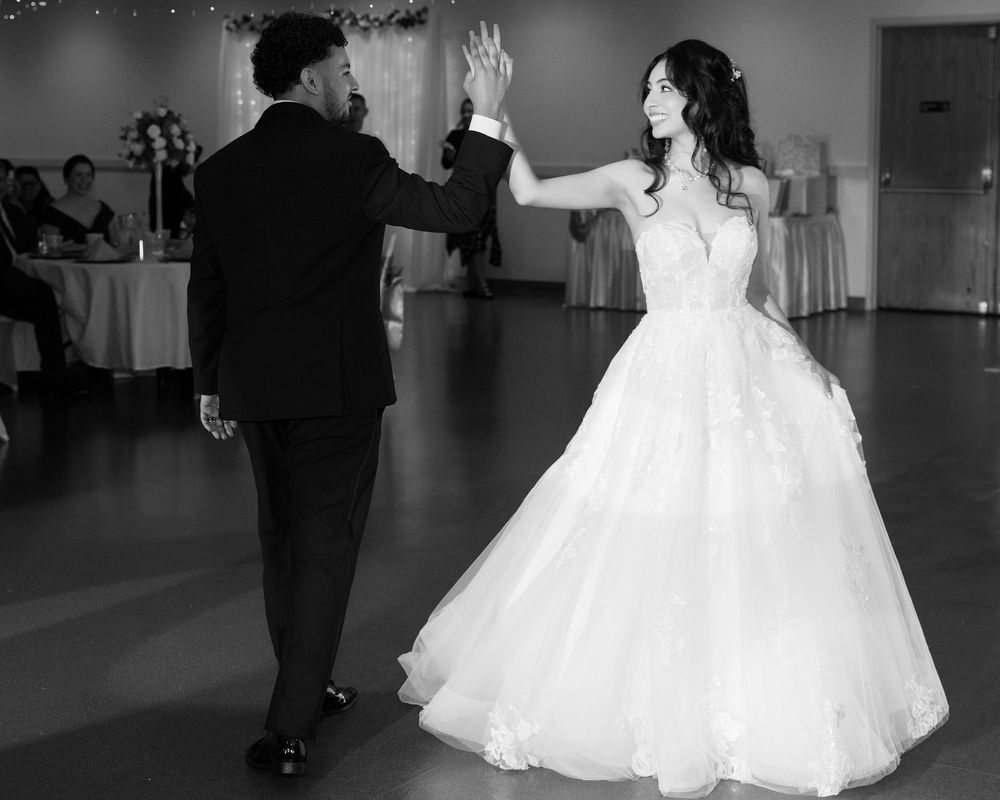 Bride and groom share a romantic first dance in black and white; elegant wedding reception photography.