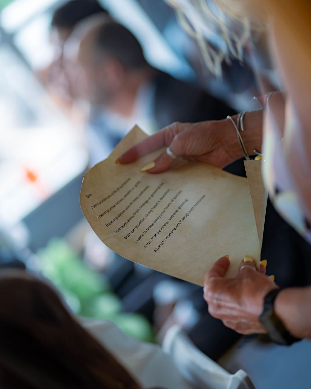 A hand holding a piece of paper with text, captured during an event with a blurred background.