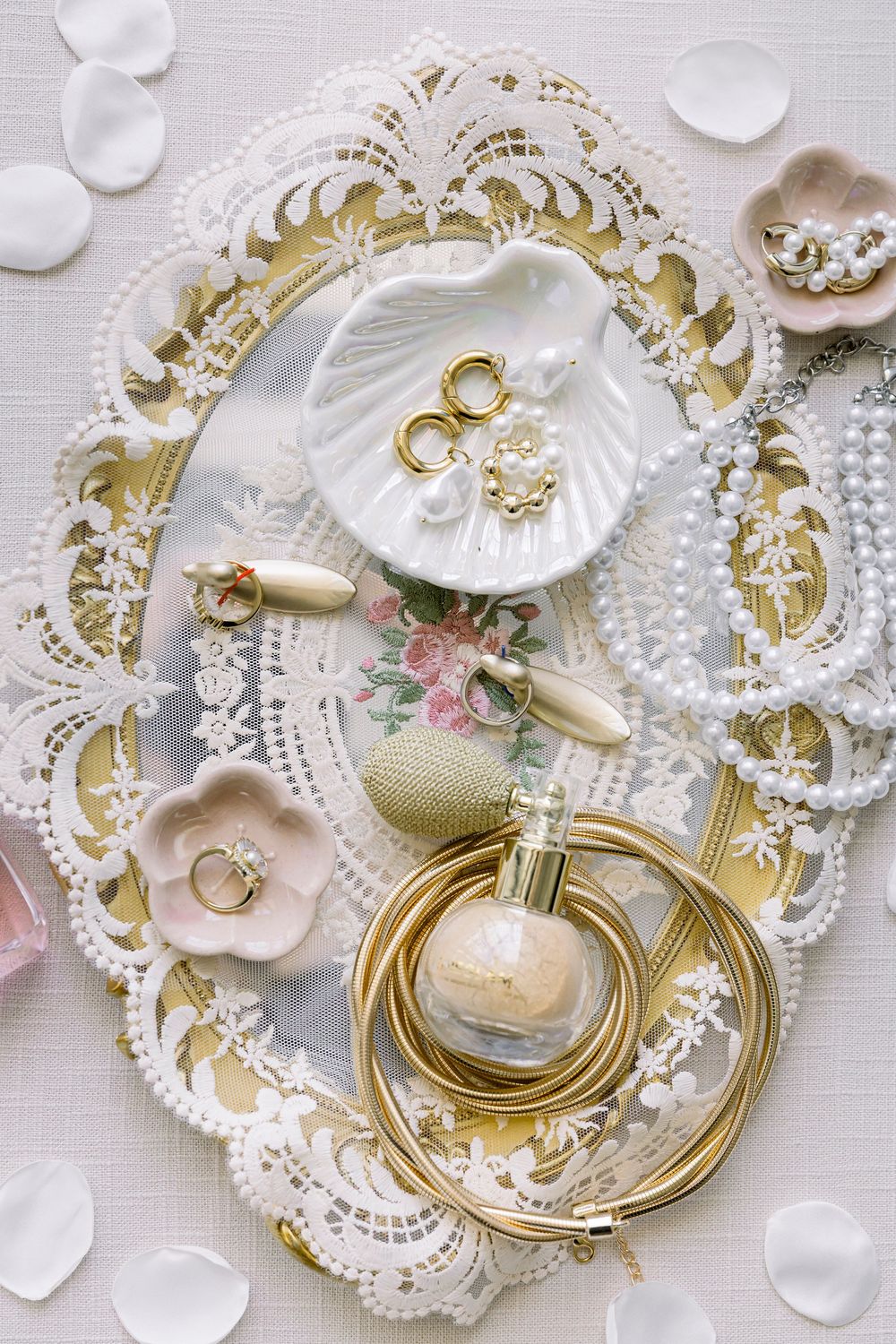 Elegant wedding details arranged on white lace doily with perfume bottle and jewelry.