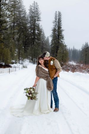 snowy winter elopement in Idaho City groom kissing bride's cheek