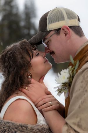 snowy winter elopement in Idaho City bride and groom nose to nose with ring hands in photo