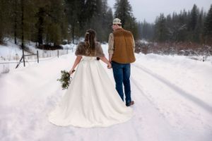 snowy winter elopement in Idaho City bride and groom walking away