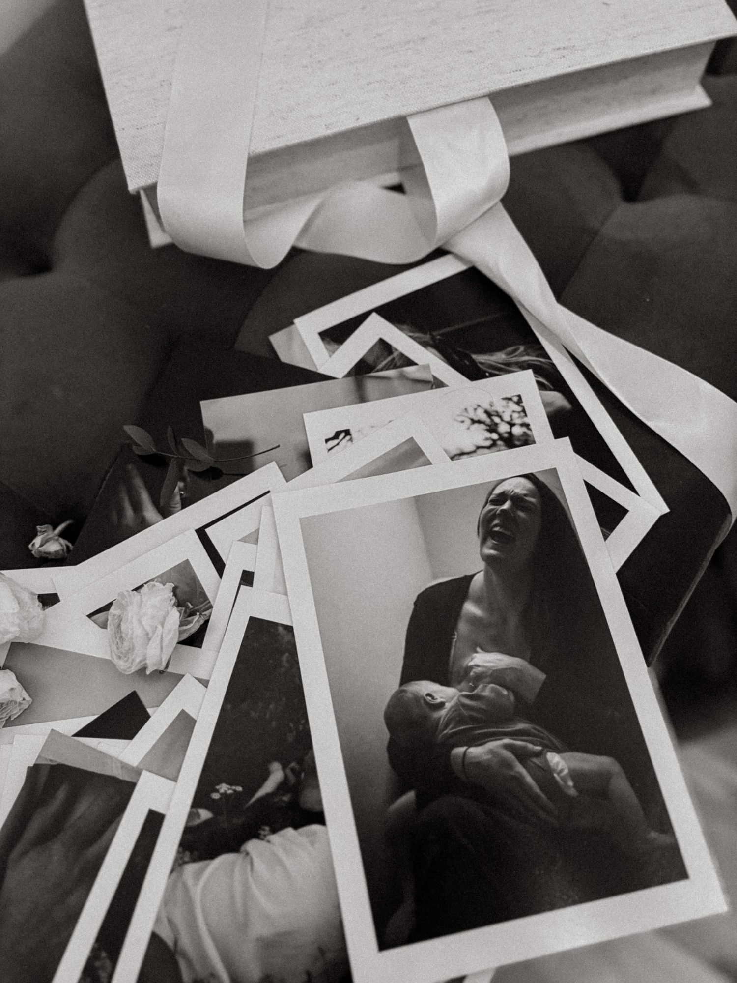 stack of photos with a photo of breastfeeding mother on top scattered on table during exhibition for Stockholm maternity photographer