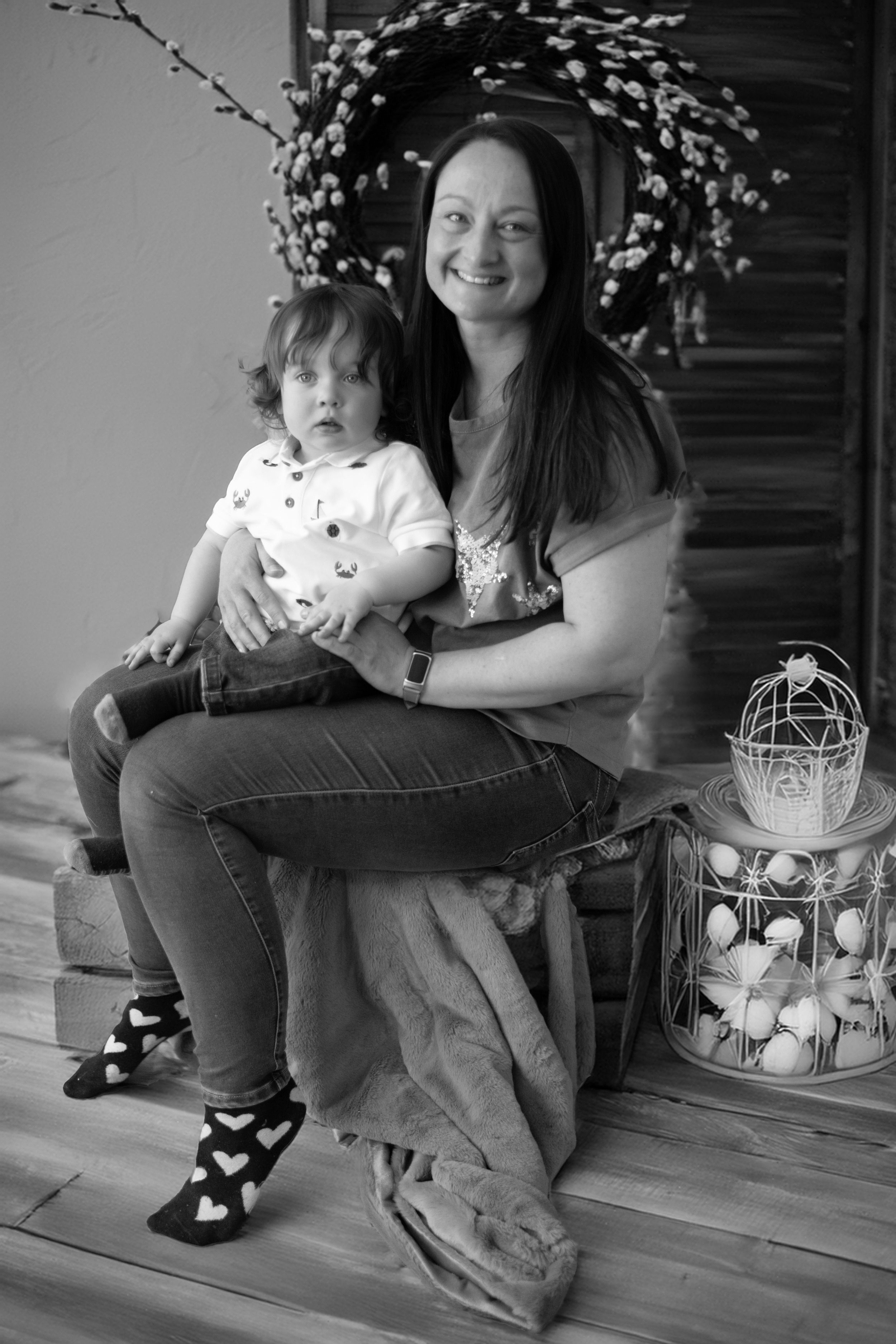 Black and white portrait taken on wooden steps with decorative wreath and lantern decor.