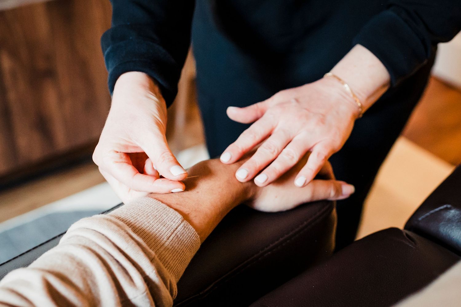 A person applying a white bandage to an injured leg on a brown surface.
