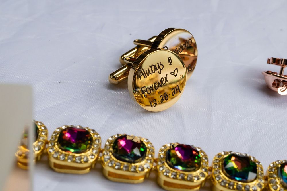 Close-up of elegant gold jewelry pieces including decorative cufflinks and bracelet with purple and green gemstones.