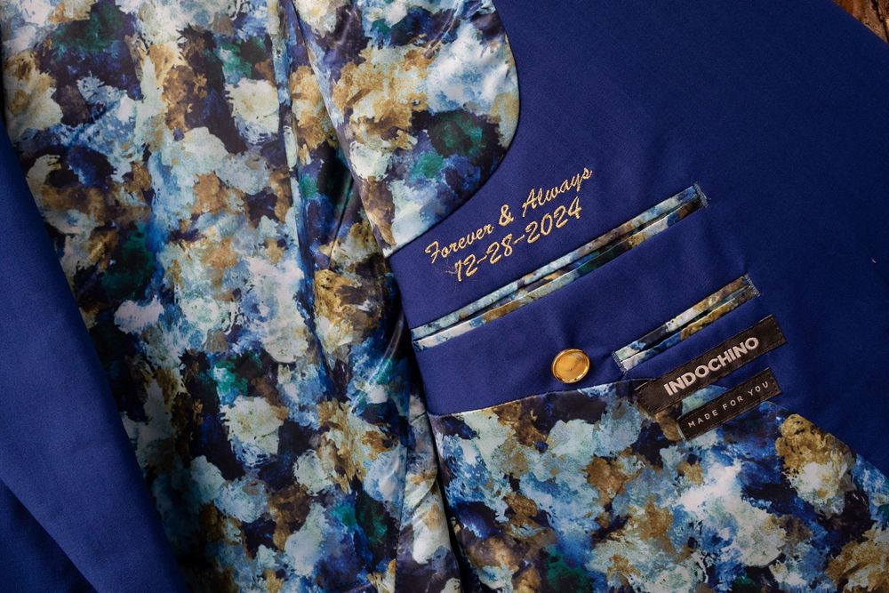 Floral patterned fabric with blue, white and gold details shown alongside a dark blue material.