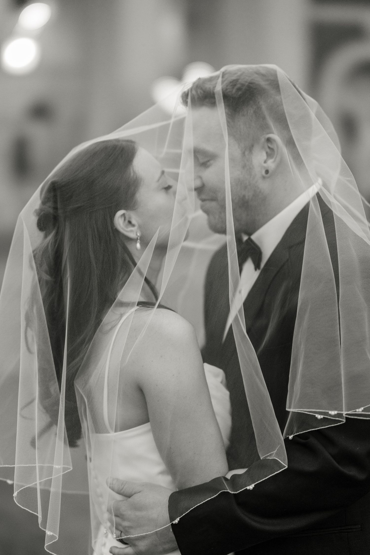 Romantic black and white wedding photo of newlyweds sharing an intimate moment under the bride's veil at Hall of Springs in Saratoga Springs