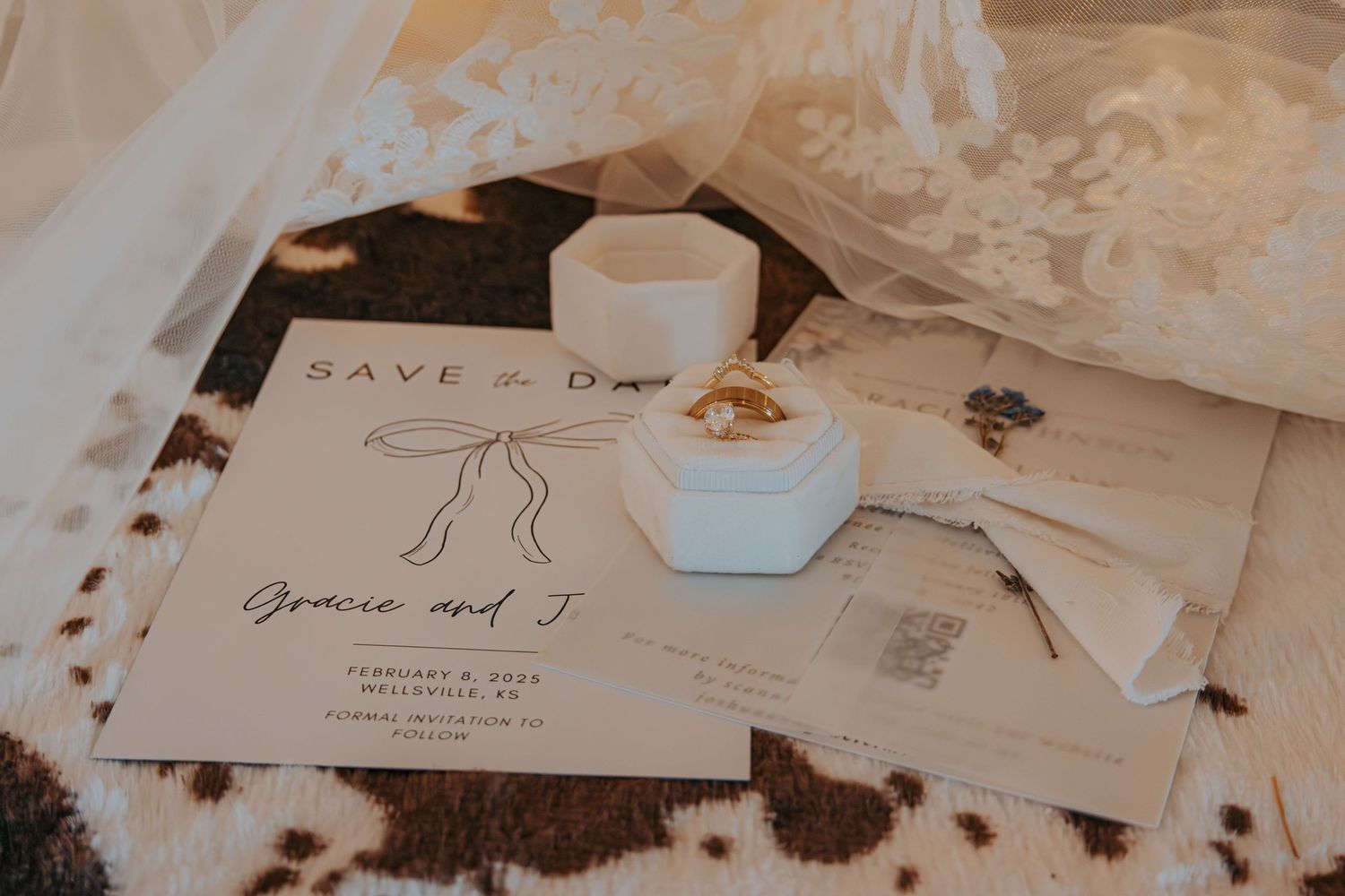 A minimalist wedding invitation with a save the date card, white ceramic ring box, and coffee cup on a textured surface.