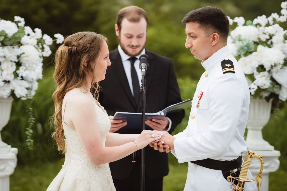 A joyful wedding ceremony unfolds outdoors with white floral arrangements and guests gathered in the garden.