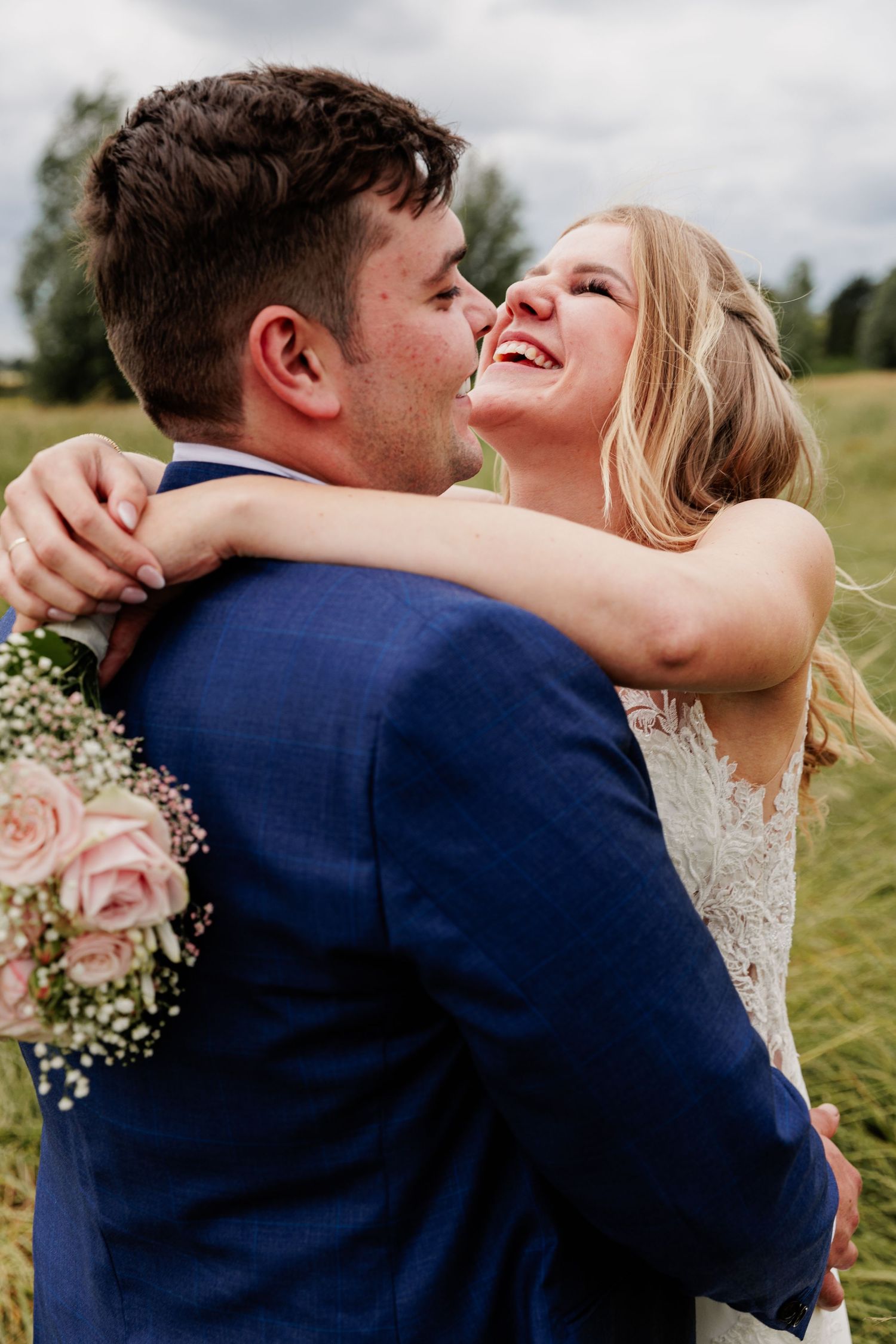 Wedding couple embracing and laughing together in an outdoor countryside setting.