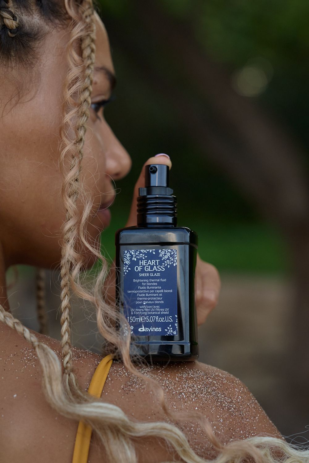 Close-up of black skincare bottle being showcased against a glittery, shimmering skin texture.