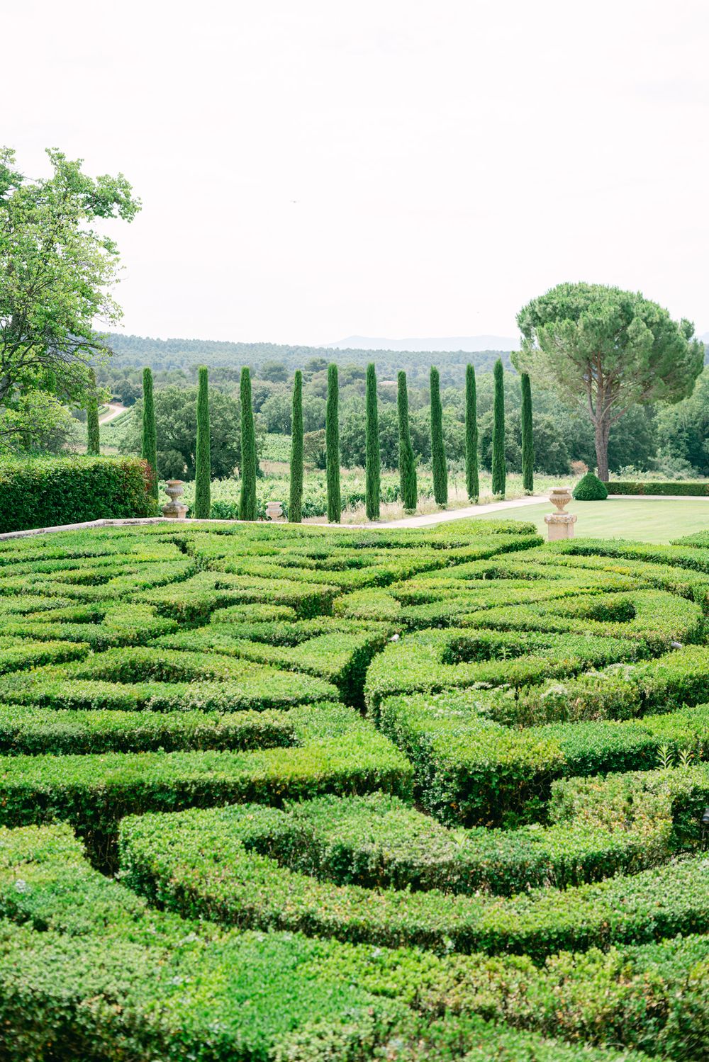 Manicured garden maze with tall cypress trees in Tuscan landscape.