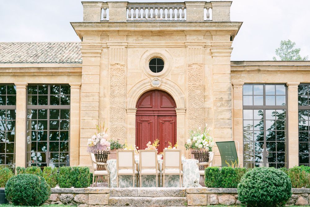 Elegant stone villa with red door and formal garden features.