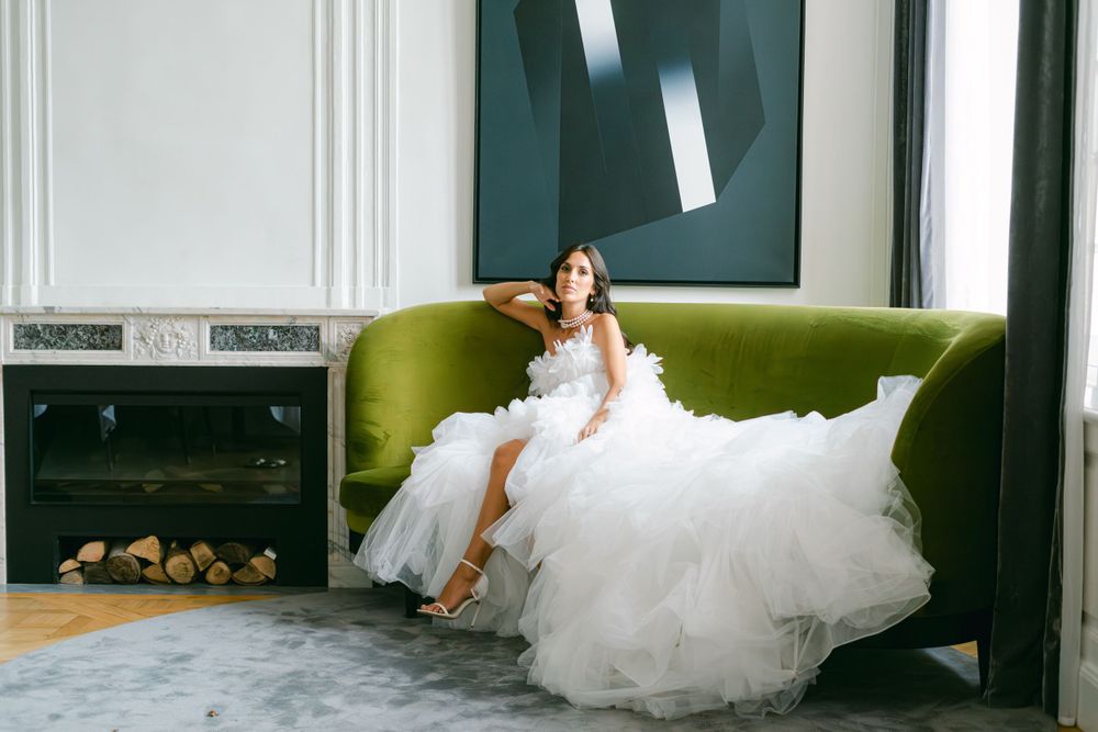 Elegant bridal portrait on olive green velvet couch with flowing white tulle gown.