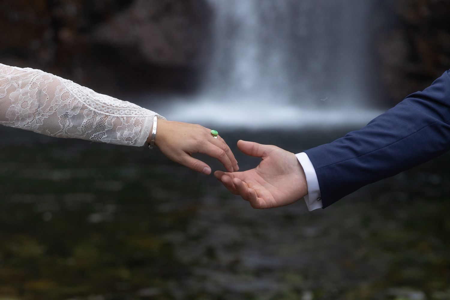 Charlie and Erin's hands reach out in front of Franklin falls during their Washington Elopement.