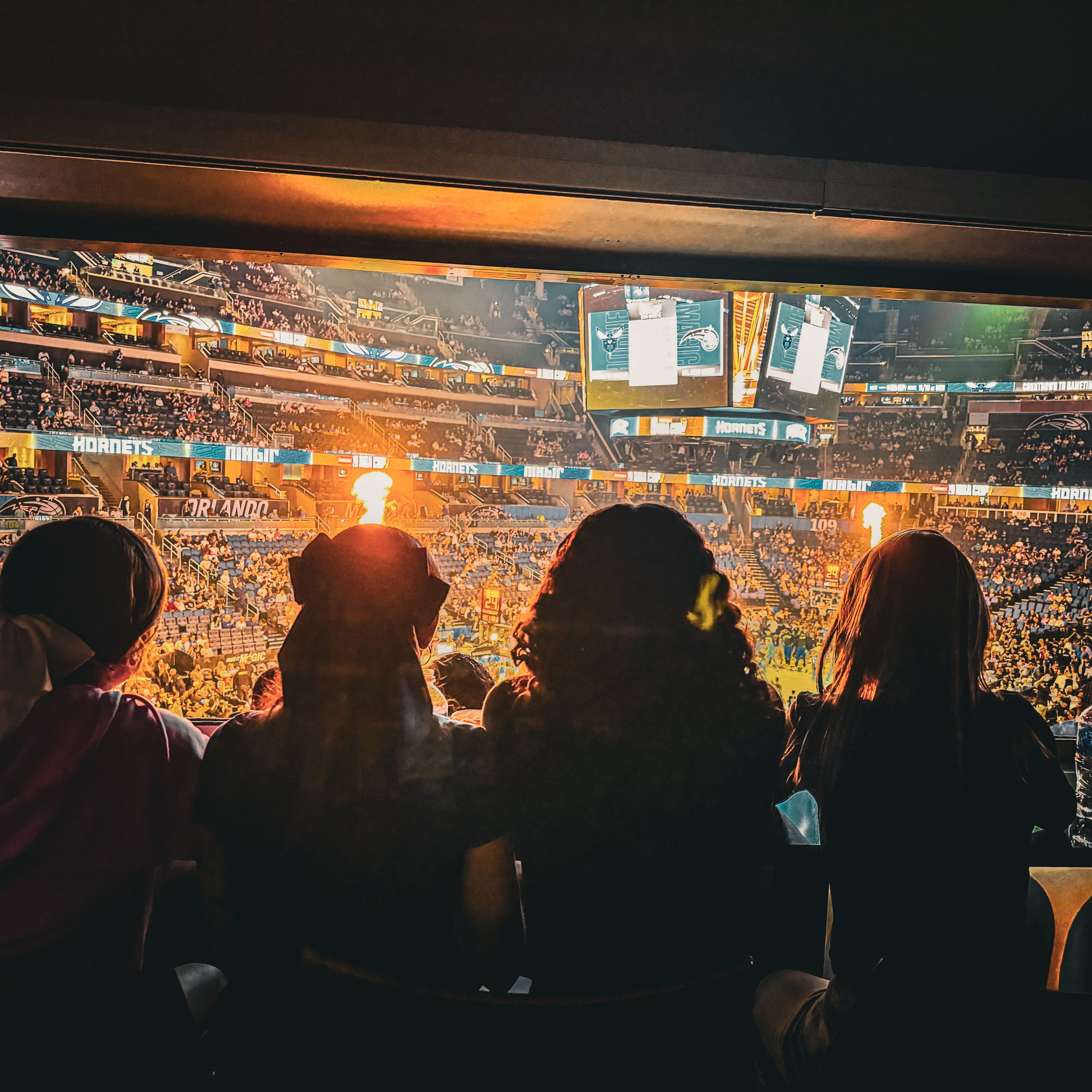 Silhouetted crowd watching a sports event in a large stadium at sunset.